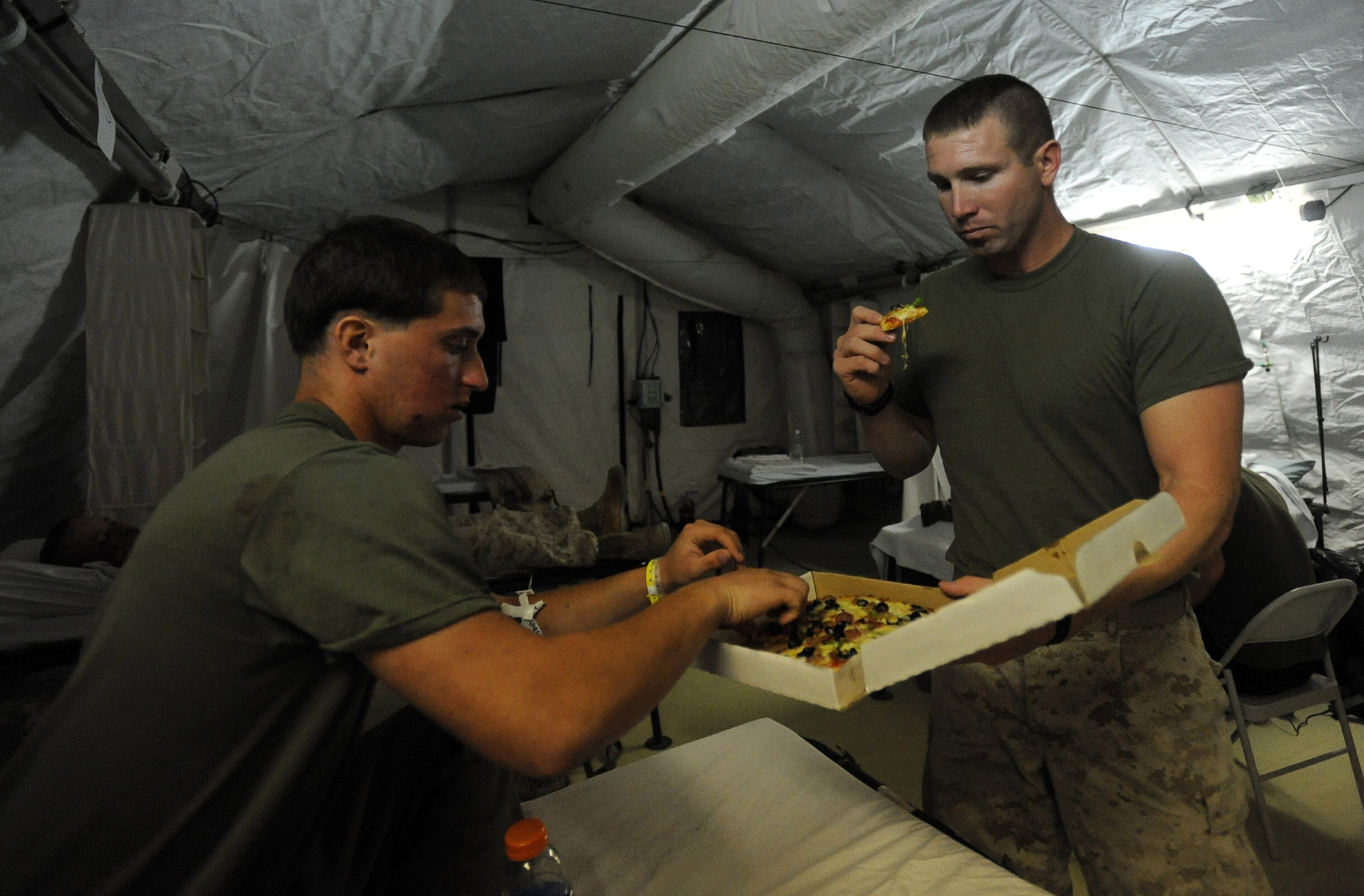 Marine Lance Cpl. Chris Spadaccini, left, a squad-automatic-weapons gunner assigned to 1/6 Marine Expeditionary Force, Bravo Company, 3rd Platoon and Marine Cpl. Keth Moss, 3rd Recon Battalion, 3rd Force Recon, share a pizza and chat at the 451st Expeditionary Aeromedical Evacuation Squadron, Detachment 1 Contingency Aeromedical Staging Facility, April 13, 2010, at Camp Bastion, Afghanistan. ?The people here have been great, they gave me some clean clothes, a hot shower and I got some Pizza,? Lance Corporal Spadaccini said. ?They have been patching me up and making me feel at home. I know they will help get me back on my feet so I can rejoin my unit. I miss them already.? (U.S. Air Force photo/Staff Sgt. Manuel J. Martinez/released)