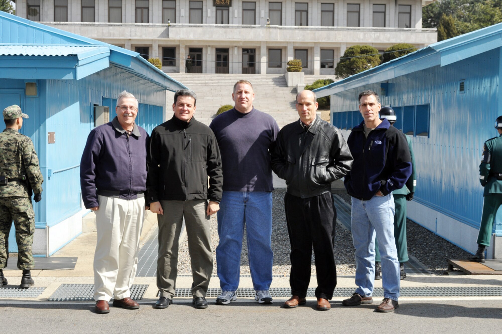 (from left) Maj. Gen. Martin Mazick, Major Gen. Frank Padilla, Maj. John Carkin, Col. Jeff Mineo and Lt. Col. Joe Battaglia pose for a photograph at the demilitarized zone in South Korea. The gray building in the background is a headquarters building in North Korea. The generals made a visit to March’s 701st Combat Operations Squadron while the squadron was deployed to South Korea last month. (U.S. Air Force photo)
