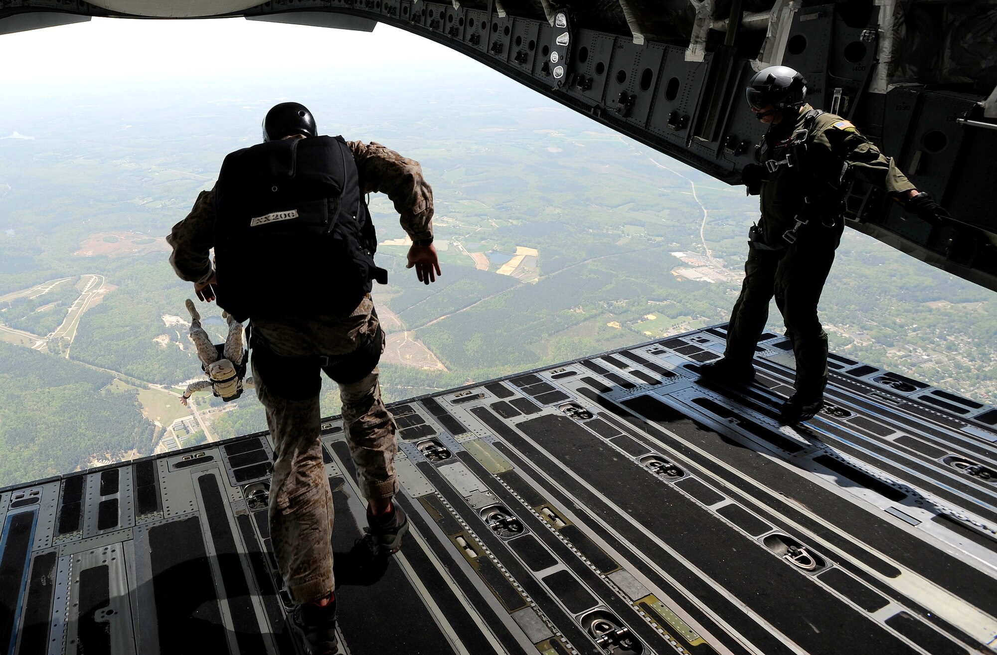 Navy SEALs jump from the ramp of a C-17 Globemaster III over Fort Picket Maneuver Training Center, Va., as Tech. Sgt. Justin Mulder looks on, April 15.  The jump was part of joint training exercise with the 517th Airlift Squadron from Elmendorf Air Force Base, Alaska. The training consisted of high altitude, high opening and high altitude, low opening jumps between 5,000 and 12,500 feet. Sergeant Mulder is a loadmaster with the 517th AS.  (Air Force photo by Staff Sgt. Brian Ferguson)