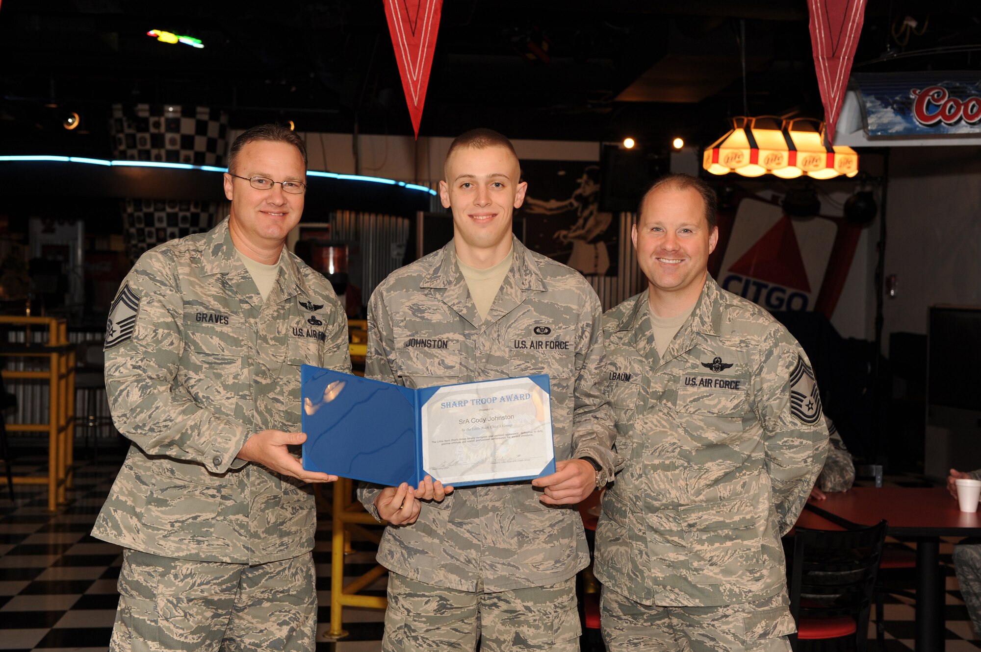 Chief Master Sgt. Fred Graves II (left) , 314th Operations Group superintendent,  and Chief Master Sgt. Gregg Kollbaum (right), 53rd Airlift Squadron superintendent, presents Senior Airman Cody Johnston  (center), 61st Airlift Squadron aviation resource management specialist, with the Chief’s Sharp Troop Award April 15. The Little Rock Chief’s Group presents the Sharp Troop Award to Airmen across Little Rock Air Force Base who exceed the standards in personal appearance, dedication to duty, positive attitude and overall professional performance. (U.S. Air Force photo by Staff Sgt. Chad Chisholm)