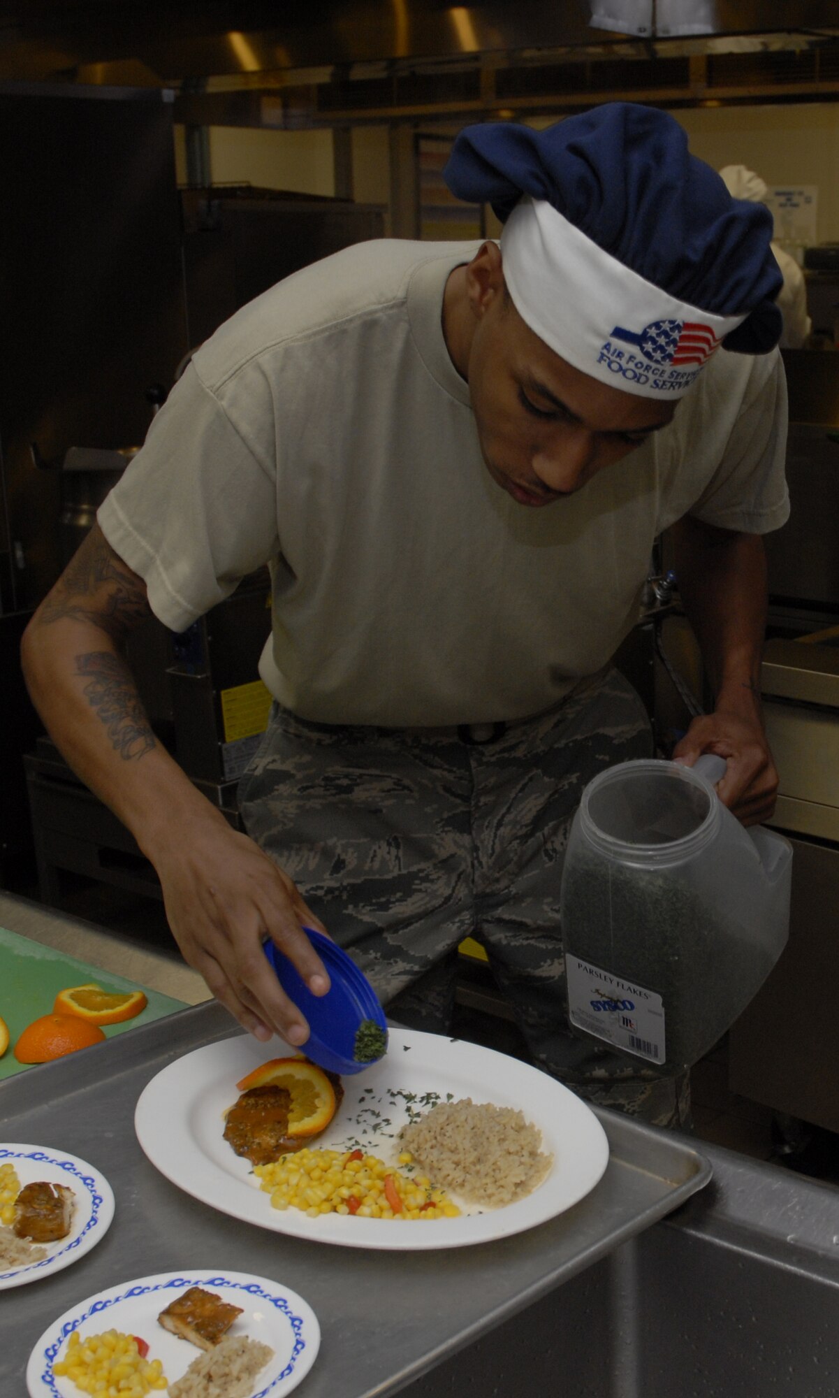 Airman1st Class Nicholas McCants, 1st Special Operations Force Support Squadron, sprinkles a parsley garnish to this dish, "Grandma's Secret," during the chef of the quarter competition at the Riptide dining facility at Hurlburt Field April 13. A panel of four judges sampled the dishes and picked them based on their taste, presentation, creativity and originality. (DoD photo by U.S. Air Force Airman 1st Class Joe McFadden) (Released)