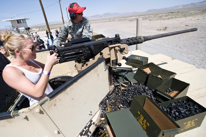 NEVADA TEST AND TRAINING RANGE --  Singer,  LeAnn Rimes, fires a M2 HB .50cal Heavy Machine Gun as Staff Sgt. Joshua Svendsen, instructor, 99th Ground Combat Training Squadron looks on.   Ms. Rimes and other country music stars toured the ground combat training facility before the Academy of Country Music's USO concert at Nellis Air Force Base April 17, 2010. (U.S. Air Force photo by Lawrence Crespo)
