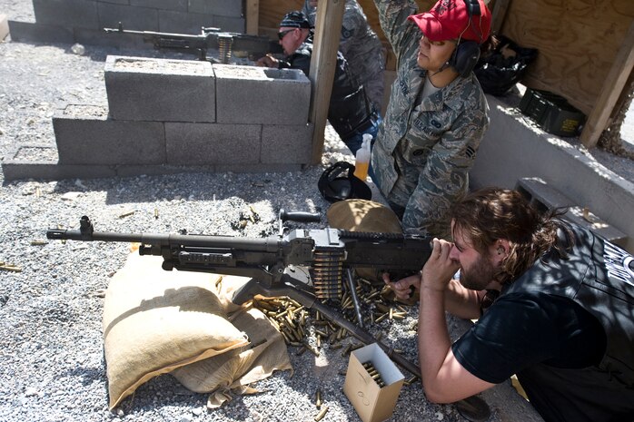 NEVADA TEST AND TRAINING RANGE --  Singer, Randy Houser, fires a M240B, machine gun as Senior Airman Alvernita Payne, 99th Ground Combat Training Squadron provides instruction to country music stars who toured the ground combat training facility before the Academy of Country Music's USO concert at Nellis Air Force Base, April 17, 2010.    (U.S. Air Force photo by Lawrence Crespo)
