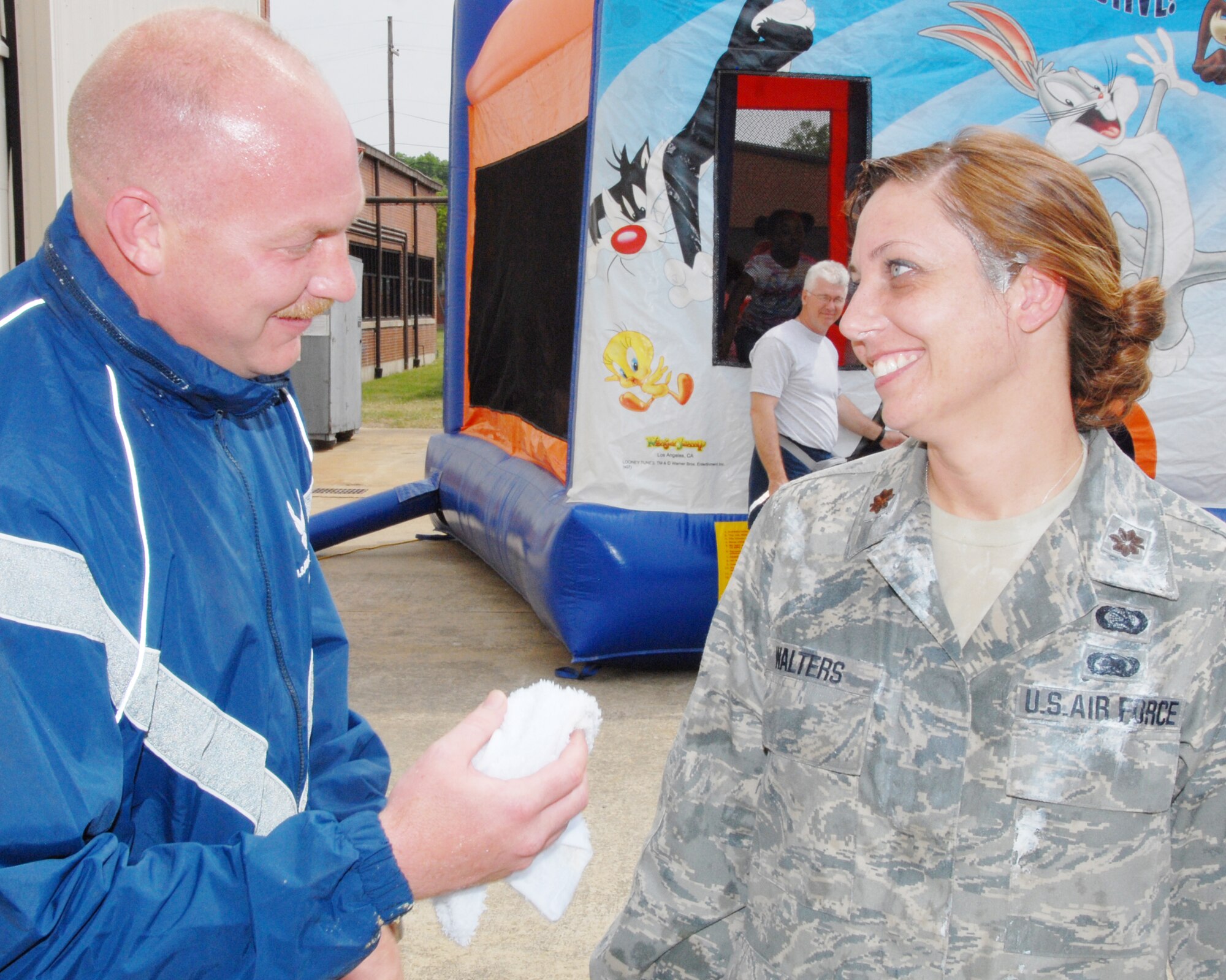 Tech. Sgt. Joshua Adams,189th Security Forces Squadron, offers Maj. Patricia Walters, 189th Communications Flight commander, a helping hand after giving her a pie in the face. (U.S. Air Force photo by Staff Sgt. Julian Johnson)