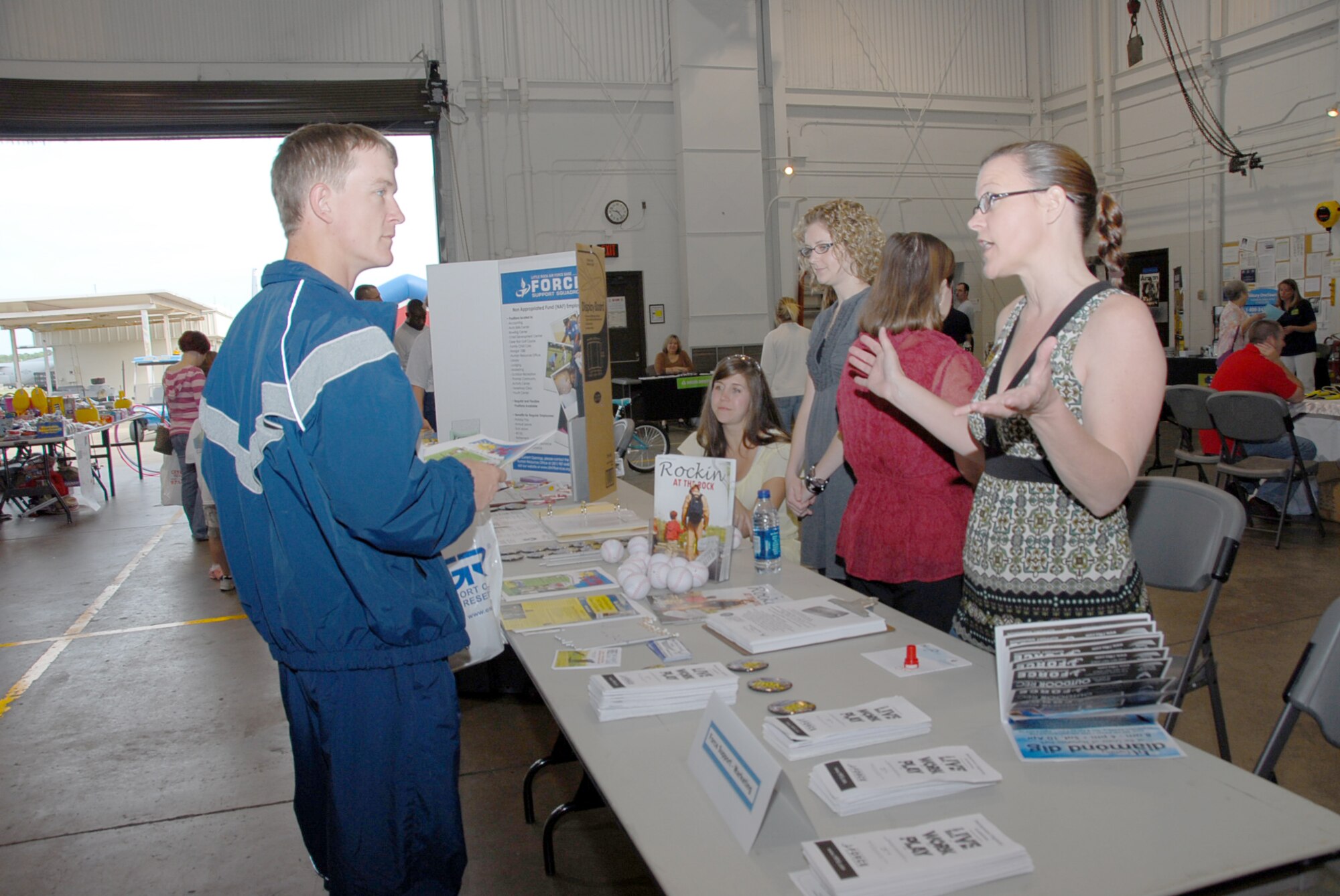 Jeanette Batchelor, 19th Force Support Squadron marketing director, explains benefits available in Rock'n at the Rock, a monthly base program magazine, to Staff Sgt. Kenneth Mitchell, 189th Airlift Wing engine shop. (U.S. Air Force photo by Master Sgt. Dianna Seerey)