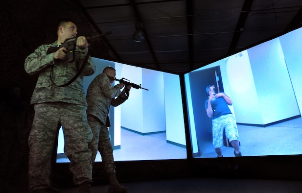 JOINT BASE MCGUIRE-DIX-LAKEHURST, N.J. – Capt. Joe Wall, 21st Air Mobility Operations Squadron Integration Flight commander, watches as Master Sgt. John MacDonald, 819th Global Support Squadron Force Protection Flight NCO-in-charge, engages a knife-wielding attacker in the 621st Contingency Response Wing’s new virtual firearms training simulator here April 15.  The system includes a modern-day “Hogans Alley” of various interactive characters to hone an Airman’s decision making process and weapons handling skills under stress.  (U.S. Air Force photo/Tech. Sgt Parker Gyokeres)