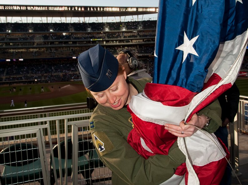 Captain Stacey Meiser,  a pilot with the 133rd Airlift Wing, gathers the flag in her arms preparing for raising the flag at the first night game at Target Field in Minneapolis Apr. 16.
U.S. Air Force Photo by Tech. Sgt. Erik Gudmundson (released)