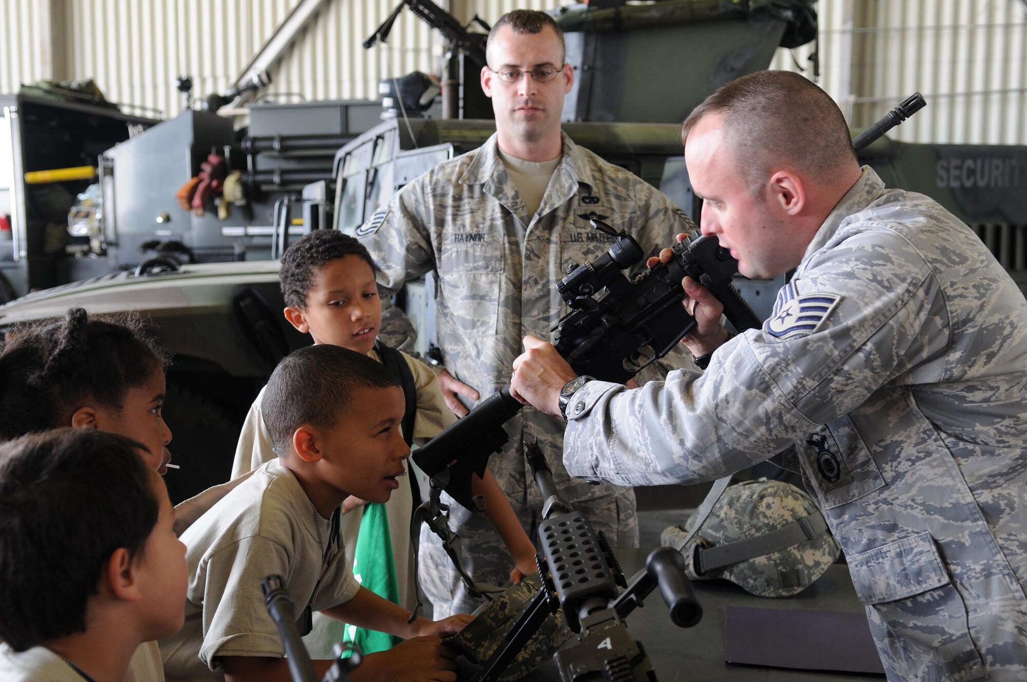 Staff Sgt. Stewart Burns, 39th Security Forces Squadron, shows kids an M-4 rifle while their military training instructor, Tech. Sgt. Lee Haynor, 728th Air Mobility Squadron, observes during Operation Born Ready and Trained, a children’s mock deployment, Friday, April 16, 2010 at Incirlik Air Base, Turkey.  Operation BRAT was coordinated by the Airman and Family Readiness Center. (U.S. Air Force photo/Senior Airman Ashley Wood)