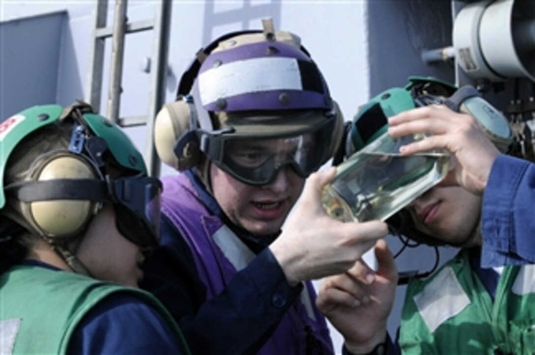 U.S. Navy Petty Officer 2nd Class Victor Chavez and Petty Officer 2nd Class Joel Erico look for particles in a JP-5 fuel sample before flight operations aboard the U.S. 7th Fleet command ship USS Blue Ridge (LCC 19) underway in the Pacific Ocean during a spring deployment on April 15, 2010.  The Blue Ridge serves under Commander, Expeditionary Strike Group 7/Task Force 76, the Navy's only forward-deployed amphibious force.  The ship is the flagship of Commander, U.S. 7th Fleet.  