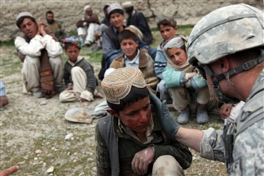 A U.S. Army medic treats an Afghan child for sunburn in the village of Meryanay in the Kherwar district of the Logar province of Afghanistan on April 9, 2010.  Coalition forces are conducting a mission to check on humanitarian conditions of area villages and help maintain security.  