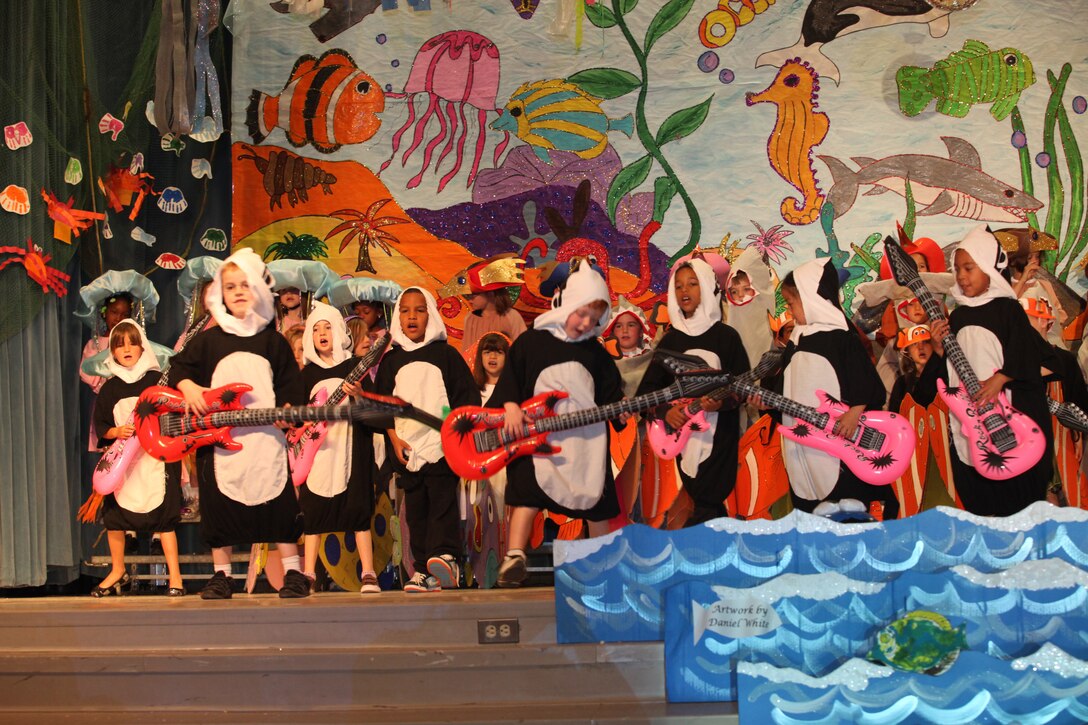 Children dressed as orca whales at Johnson Primary School aboard Marine Corps Base Camp Lejeune play inflatable guitars and saxophones during their spring musical, “Oceans of Fun,” April 20.  The kindergarten, 1st grade and 2nd grade students learned about ocean animals and their habitats in celebration of Earth Day and Month of the Military Child.