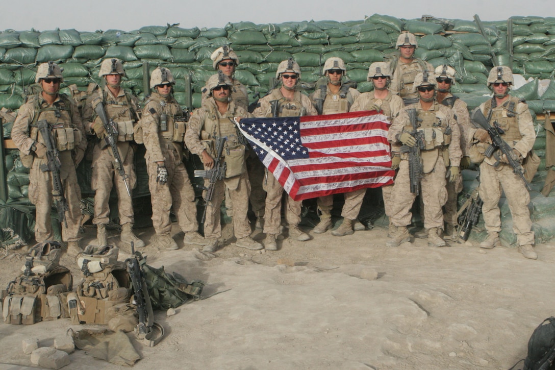 Marines from Easy Company, 2nd Battalion, 2nd Marine Regiment, pose holding an American flag shortly before leaving Patrol Base Khodi Rhom in Garmsir District, Helmand province, Afghanistan, April 20. Marines alongside a section of Afghan National Army soldiers, man PB Khodi Rhom to patrol and observe an area once known for large amounts of enemy activity.