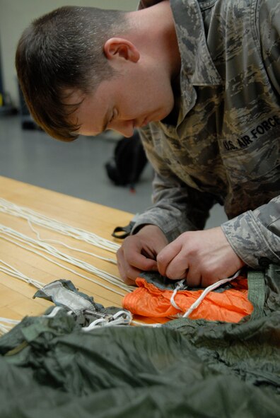 KUNSAN AIR BASE, Republic of Korea -- Tech. Sgt. Jonathan Anlauf, NCOIC of Aircrew Flight Equipment assigned to the 8th Operations Support Squadron, checks the pockets of the canopy by removing the c-clip here April 7. This inspection ensures that the parachute is still serviceable and does not have any snags, tears, or rips. (U.S. Air Force photo/Staff Sgt. Darnell T. Cannady)