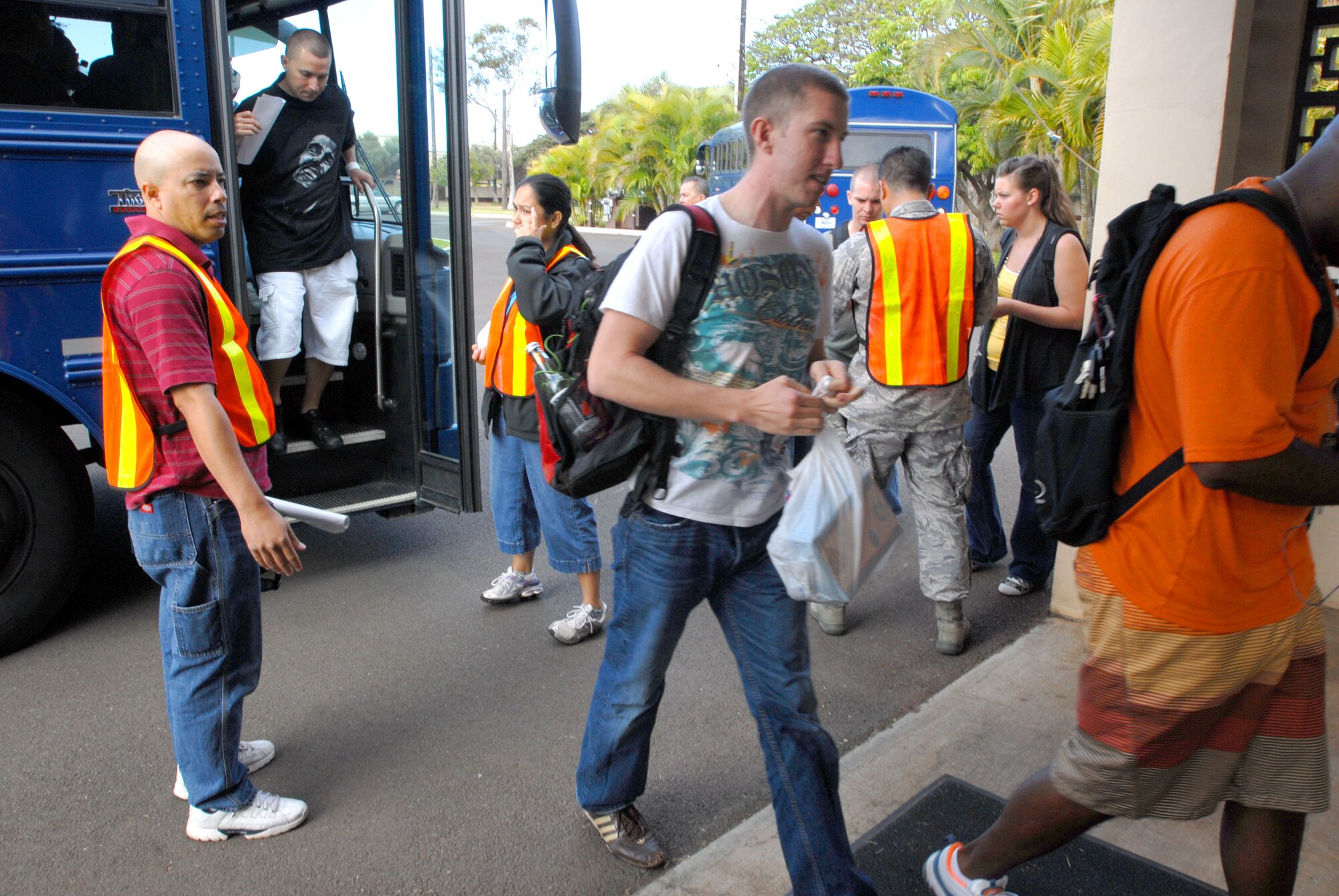 Airmen and family members acting as evacuees get off a bus on their way to the Makai Recreation Center during the Non-combatant Evacuation Operation as part of the Operational Readiness Exercise here, April 20. The NEO tests the 15th Airlift Wing's capabilities to evacuate non-combatants. (U.S. Air Force photo/Senior Airman Gustavo Gonzalez)