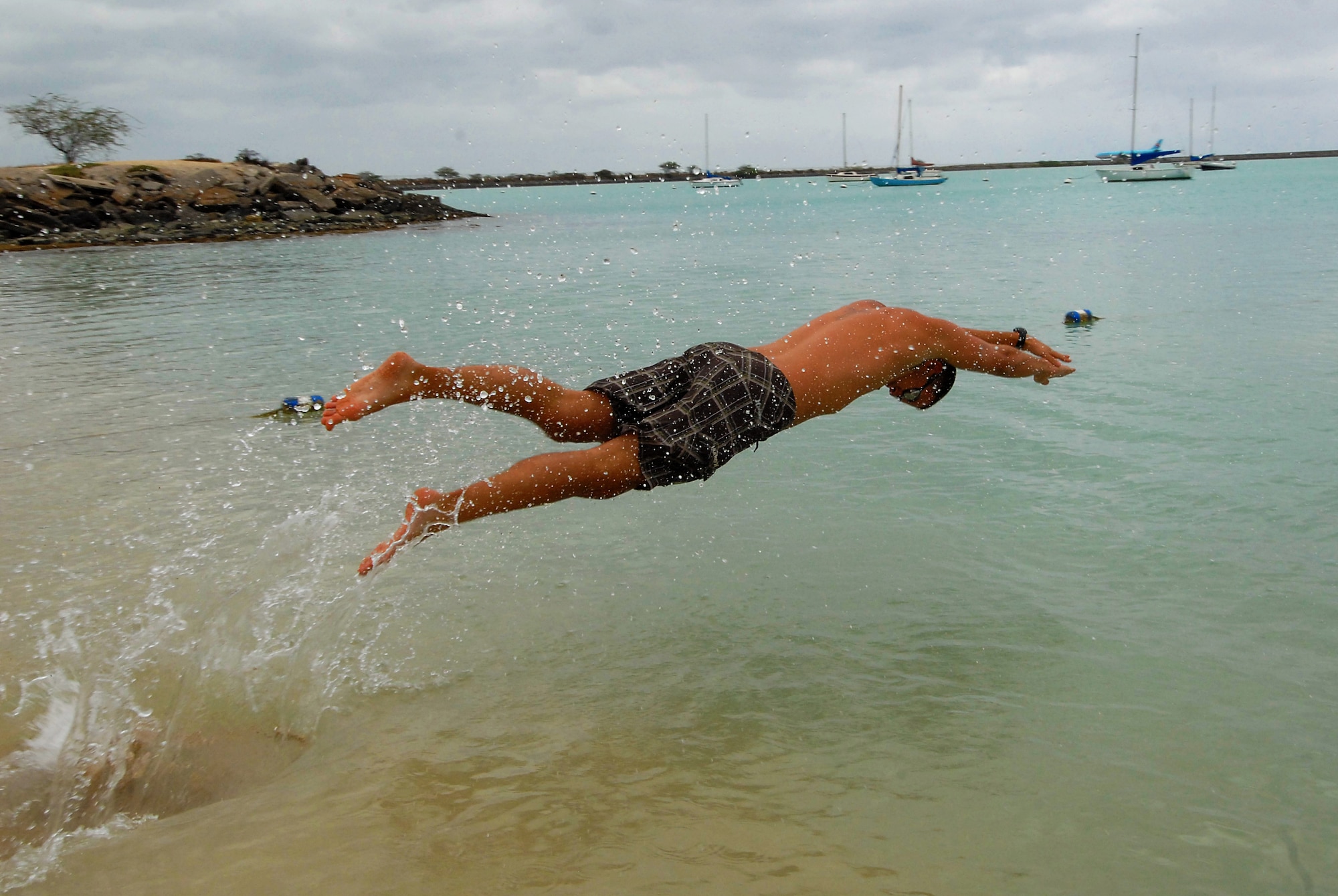 JOINT BASE PEARL HARBOR HICKAM, Hawaii -- Airman 1st Class Aaron Calvario, 324th Intelligence Squadron, leaps into Hickam Harbor during the fitness challenge portion of Hickam's annual Sports Day at Hickam Harbor April 16. The 535th Airlift Squadron won the event with a time of 6:15. The 324th IS turned in the second best time at 6:21 and the 15th Operations Support Squadron turned in a sub-seven minute time to take third. The events thourghout the day included an innertube relay race, fitness challenge, volleyball, kayak races, horseshoe toss and the tug-o-war. At the end of the day, the Chiefs took down the Eagles in a volleyball game. (U.S. Air Force photo by Staff Sgt. Mike Meares)