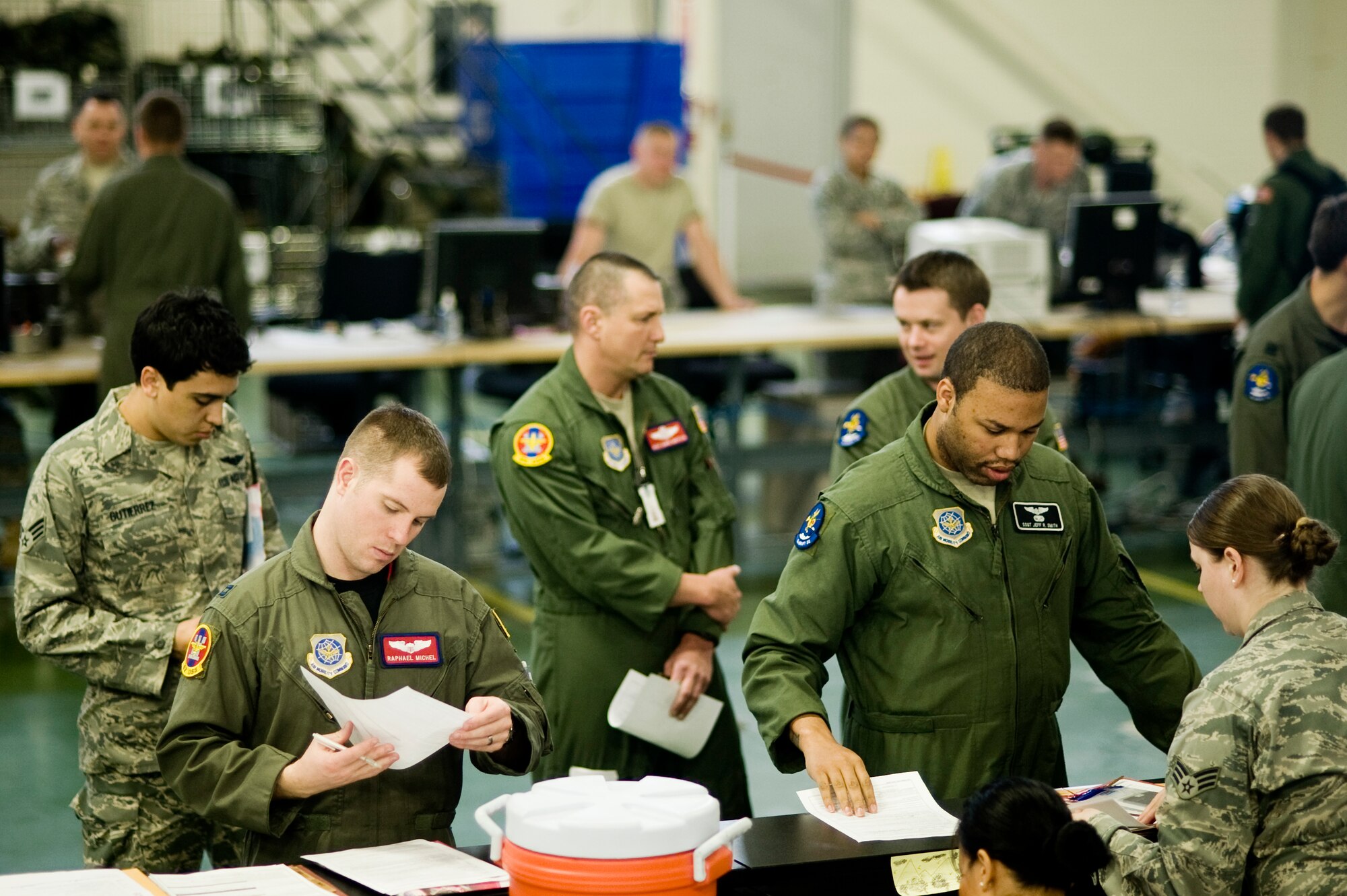 Senior Airman Joanne Sherred, 62nd Force Support Squadron, right, assists Capt. Michel Raphael Michel, 62nd Operations Squadron, and Staff Sgt. Jeff Smith, 8th Airlift Squadron, in organizing their mobility folders during a deployment processing line at the Logistics Readiness Squadron mobility warehouse April 20.  More than 100 Airmen will deploy with the 8th AS for approximately 120 days to the Middle East.  (U.S. Air Force Photo by Abner Guzman)