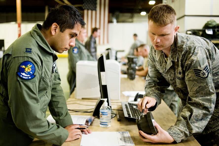 Tech. Sgt. John Hruska, 62nd Logistics Readiness Squadron, verifies the serial number on a gas mask canister while processing Capt. Omar Moreno, 8th Airlift Squadron, through a deployment processing line at the LRS mobility section April 20. (U.S. Air Force Photo by Abner Guzman)

