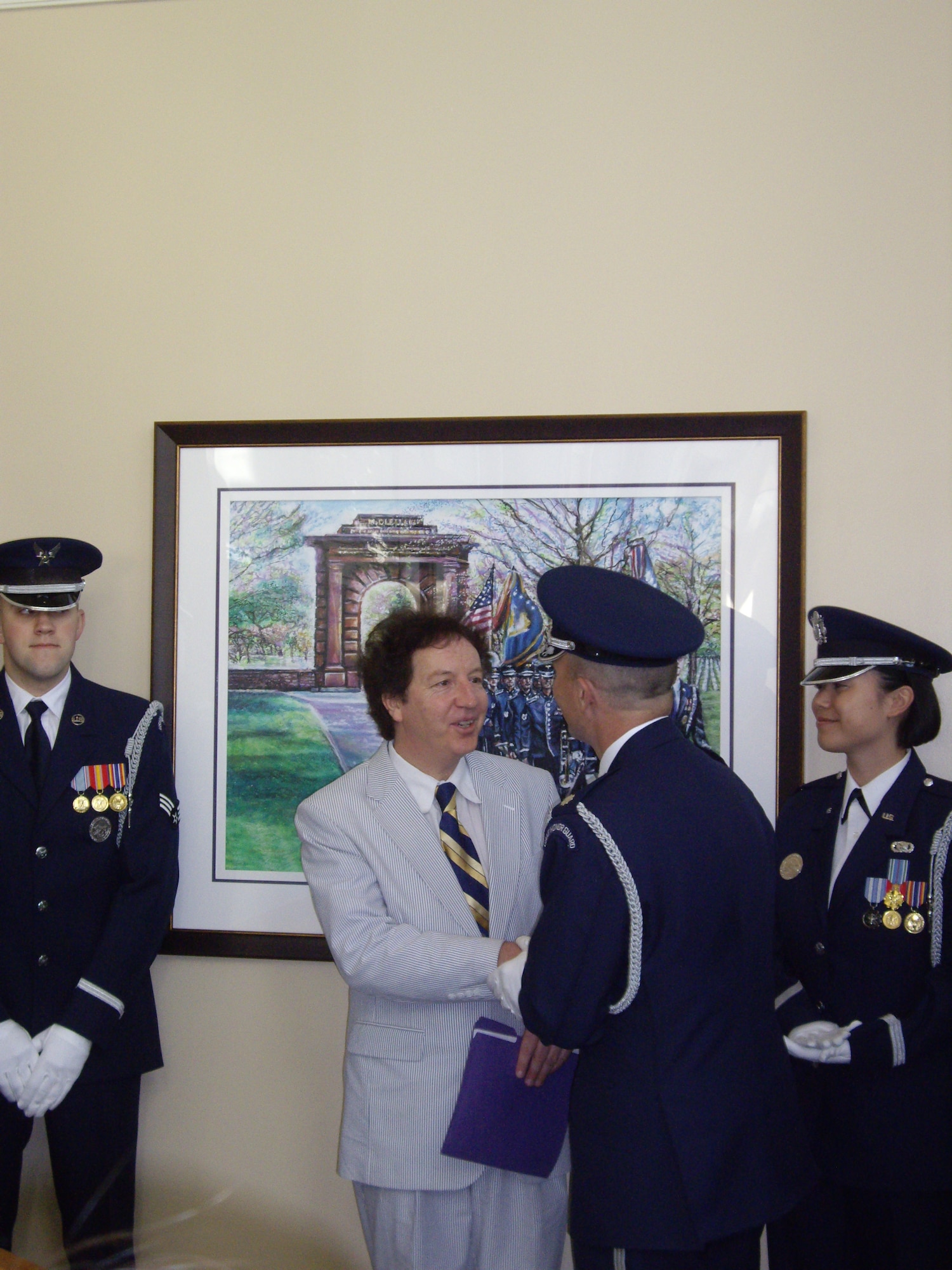 Lt. Col. Raymond Powell, commander of the U.S. Air Force Honor Guard, shakes the hand of artist Gary Schofield after the unveiling of Schofield's "The Arlington National Cemetery Painting," April 20, 2010. The painting is a gift from Mr. Schofield to the cemetery and hangs in the lobby of the Visitors Center, near the information desk.