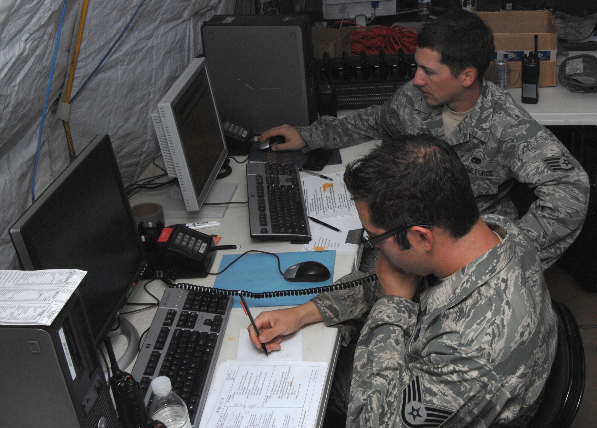 Staff Sgt. Jeremie Brashear (front) receives aircraft maintenance information over the phone, while Staff Sgt. Theodore Roberts updates an aircraft status spreadsheet on his computer. Both Airmen work the day shift at the maintenance operations center inside Angel Thunder 2010's rescue operations center. The "ROCMOC" function provides up-to-the-minute information to exercise planners on which aircraft are mission-capable for training scenarios. (U.S. Air Force photo/Staff Sgt. Jake Richmond)
