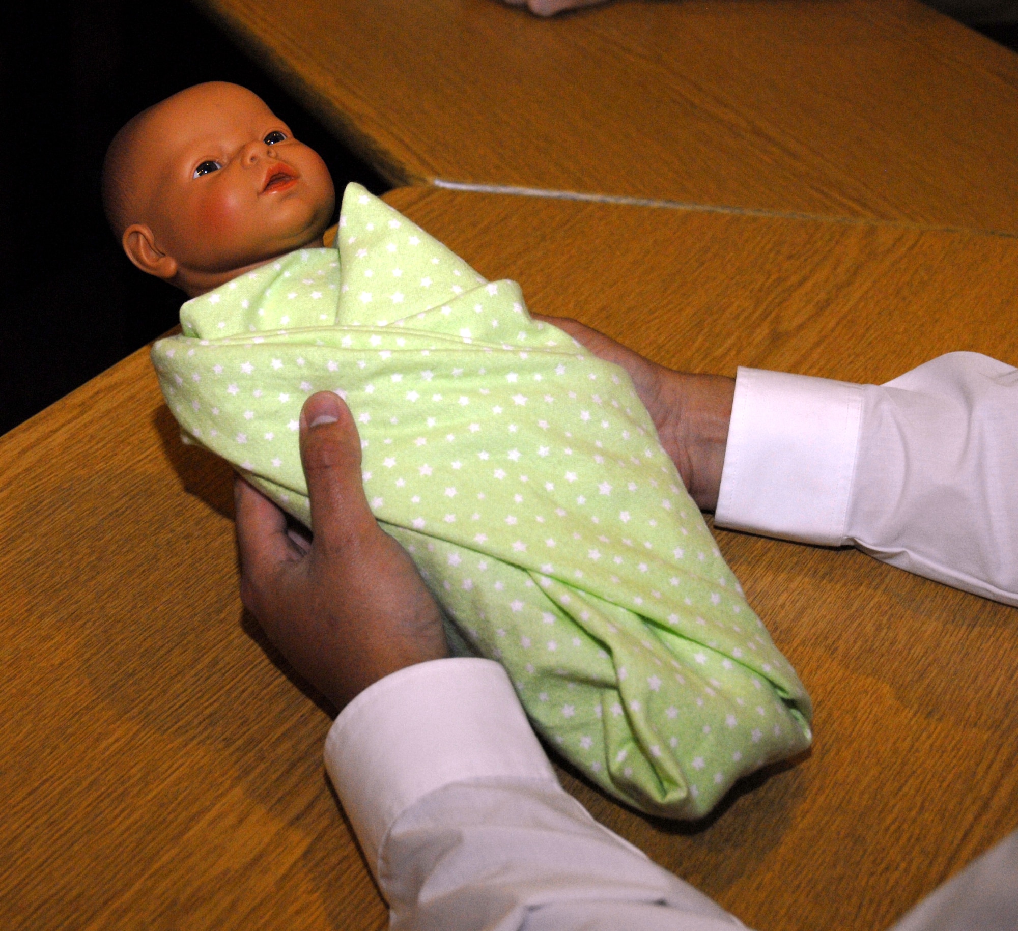 Alex Santillan, a soon-to-be father, holds up a properly-swaddled baby mannequin during the "Dads: The Basics" class at the Hurlburt Field Airman & Family Readiness Center April 14. The two-day course was designed to encourage men to share their concerns, stories and questions with fathers who are presently experiencing or have already gone through similar parenting situations. (DoD photo by U.S. Air Force Airman 1st Class Joe McFadden) (RELEASED)