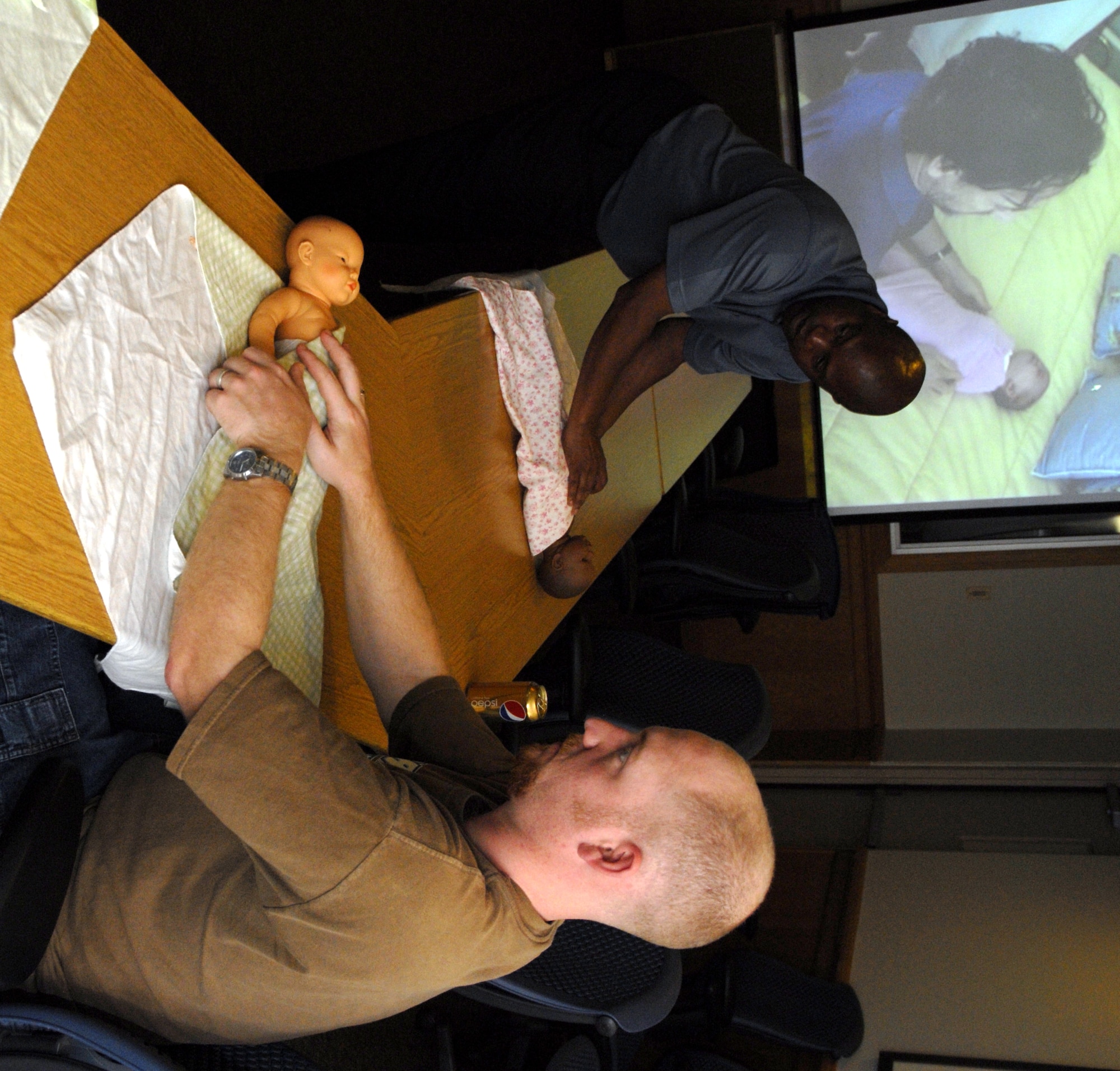 Gary Scott, a Family Advocacy Program assistant with the 1st Special Operations Medical Operations Squadron, left, checks with his class while properly swaddling a baby mannequin as Jeffrey Logan, a new father, right, also practices during the "Dads: The Basics" class at the Hurlburt Field Airman & Family Readiness Center April 14. The two-day course was designed to encourage men to share their concerns, stories and questions with fathers who are presently experiencing or have already gone through similar parenting situations. (DoD photo by U.S. Air Force Airman 1st Class Joe McFadden) (RELEASED)