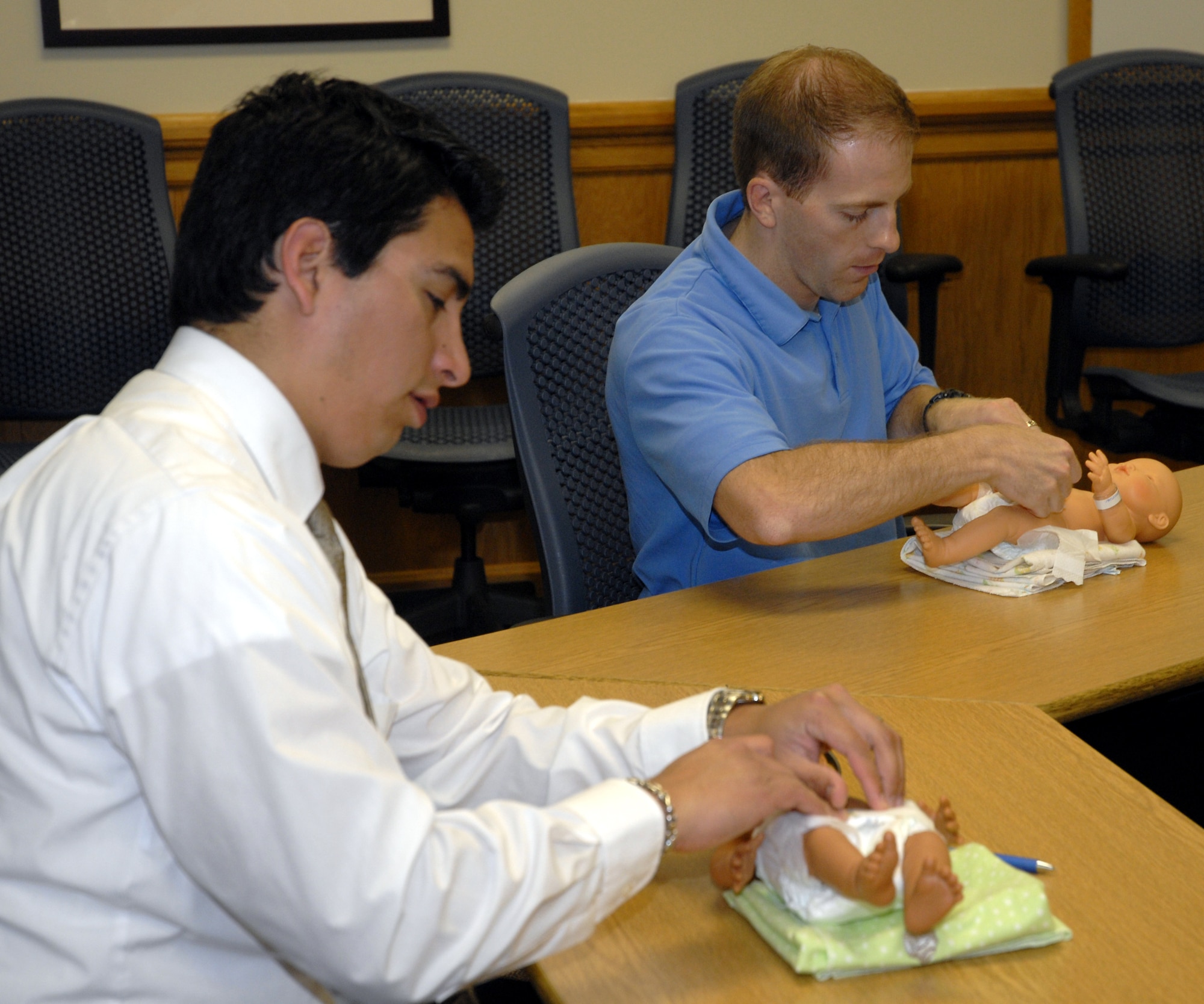 Capt. Eric Maddox, 319th Special Operations Squadron, right, and Alex Santillan, both soon-to-be-fathers, learn how to change a diaper on a baby mannequin during the "Dads: The Basics" class at the Hurlburt Field Airman & Family Readiness Center April 14. The two-day course was designed to encourage men to share their concerns, stories and questions with fathers who are presently experiencing or have already gone through similar parenting situations. (DoD photo by U.S. Air Force Airman 1st Class Joe McFadden) (RELEASED)