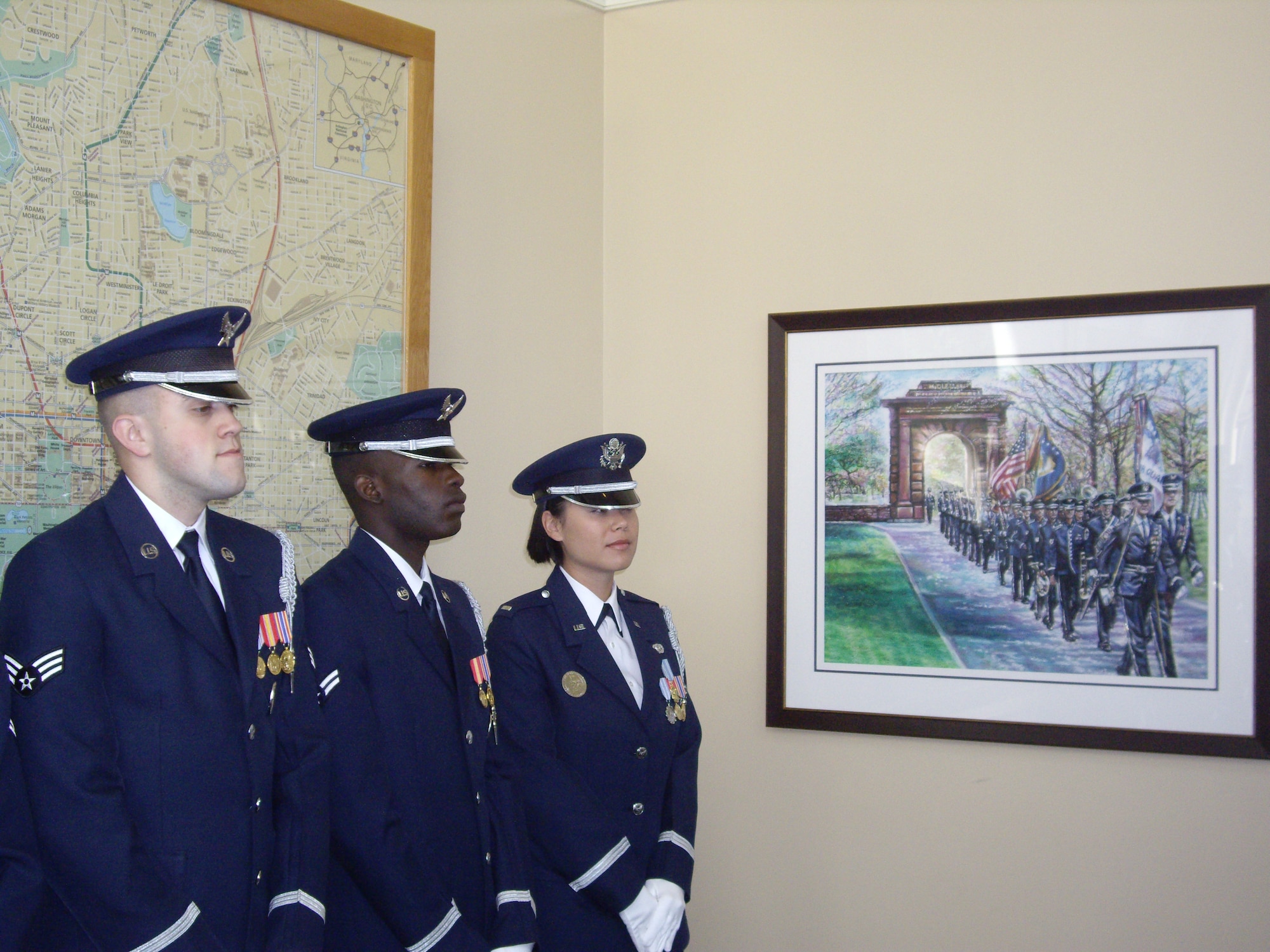 Members of the U.S. Air Force Honor Guard observe Gary Schoefield's donated piece, "The Arlington National Cemetery Painting." Schoefield depicted guardsmen underneat teh McClellen Arch during a funeral procession. 