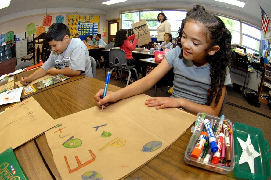 Travis Elementary 2nd grade students Jayden Stokes, right, and Jacob Hermesch  work on their bag art.  The crayon colored bags will used to pack groceries  at the Travis Commissary to celebrate Earth Day.  (U.S. Air Force photo by Civ/Nan Wylie)