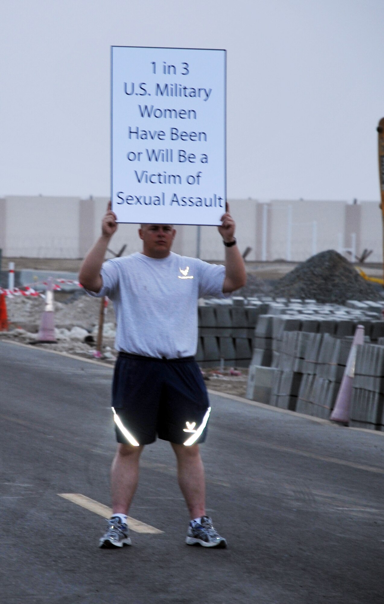 Master Sgt. Greg Ellis, from the 380th Expeditionary Logistics Readiness Squadron fuels management flight, holds up a statistics sign on sexual assault, as part of the "Walk A Mile In Their Shoes" event by the 380th Air Expeditionary Wing at a non-disclosed base in Southwest Asia on April, 19, 2010, in observance of Sexual Assault Awareness Month. Throughout a one-mile walk, signs such of this were placed while walk participants read them and walked in silence. The event was organized by Capt. Richard Laca -- the 380th AEW sexual assault response coordinator. (U.S. Air Force Photo/Master Sgt. Scott T. Sturkol/Released)