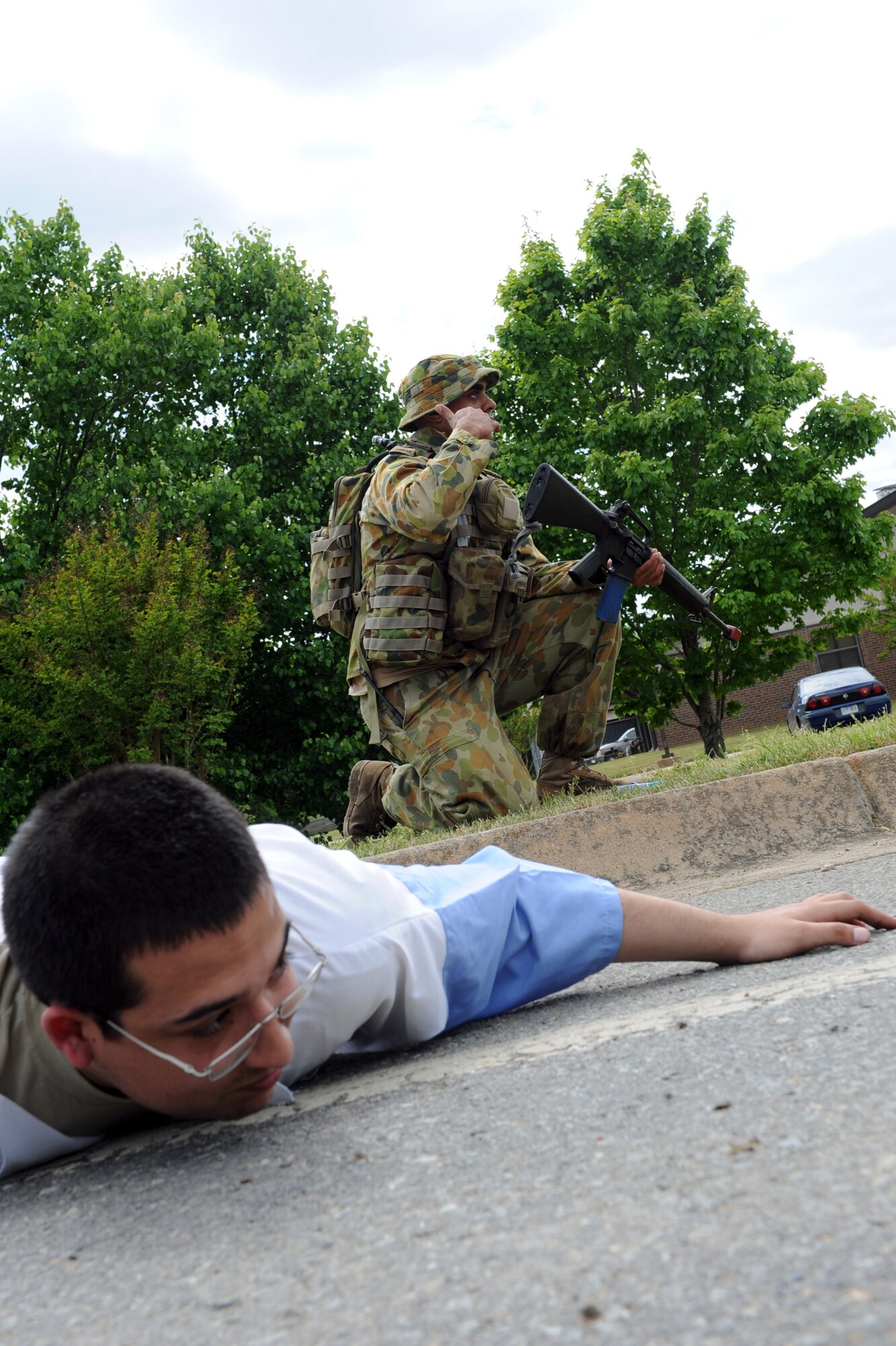 (Rear) Sergeant Nick Beamish, Royal Australian Air Force 37 Squadron airfield defense guard, signals teammates to apprehend a suspected saboteur during a security breach exercise. (Front) Senior Airman Alexander Acosta, 314th Aircraft Maintenance Squadron, acts as a combatant during a joint exercise on Little Rock Air Force Base April 19. The exercise was aimed at providing graduate-level combat airlift training to the aircrews and mobility forces. (U.S. Air Force photo by Senior Airman Ethan Morgan)