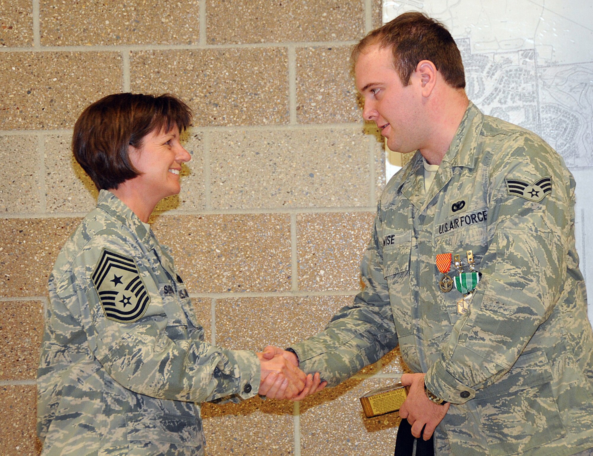 OFFUTT AIR FORCE BASE, Neb. --- Chief Master Sgt. Lisa Sirois, 55th Wing command chief, presents Senior Airman Victor Wise, 55th Security Forces Squadron, with a brick from the Martin Bomber Building during a ceremony here April 14. Airman Wise also recieved the Air Force Combat Action Medal and two Army Commendation Medals at the ceremony for his selfless actions to save lives after a convoy he was traveling in was hit by an improvised explosive device while he was deployed to Iraq. The AFCAM is awarded to Airmen who have been active participants in combat, while being under direct and hostile fire as they physically engaged hostile forces with direct and lethal fire in connection with military operations. U.S. Air Force photo by Kendra Williams 