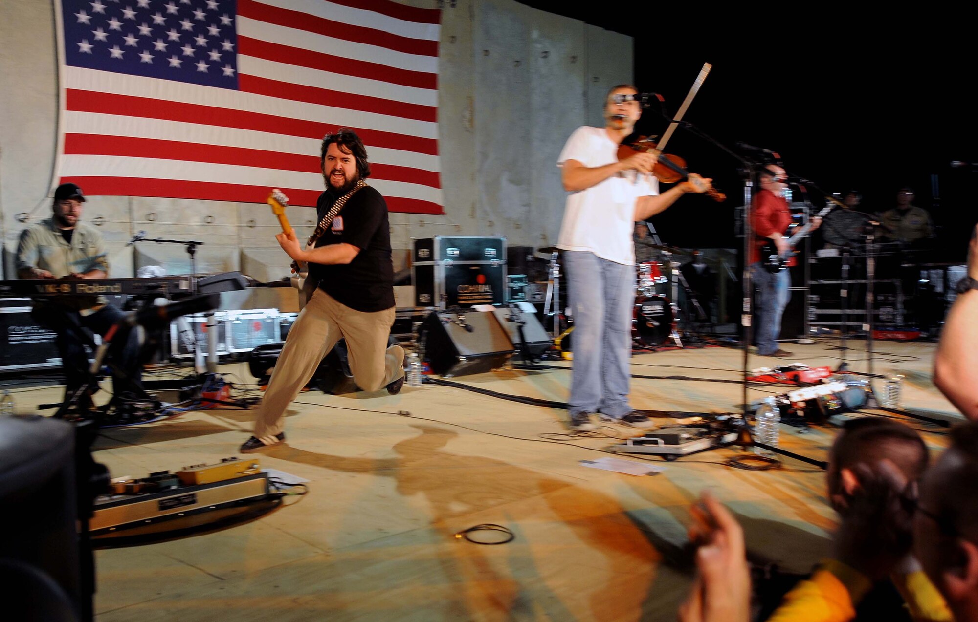 Clay Cook, a member of the Zac Brown band, runs across the stage during the performance of "Devil Went Down to Georgia" for a crowd of deployed personnel in Holt Stadium at Joint Base Balad, Iraq, April 18, 2010. The Grammy nominated band is touring various bases throughout Southwest Asia to perform for the troops rather than attend this year's Academy of Country Music Awards for which they were nominated. (U.S. Air Force photo by Master Sgt. Linda C. Miller/Released)