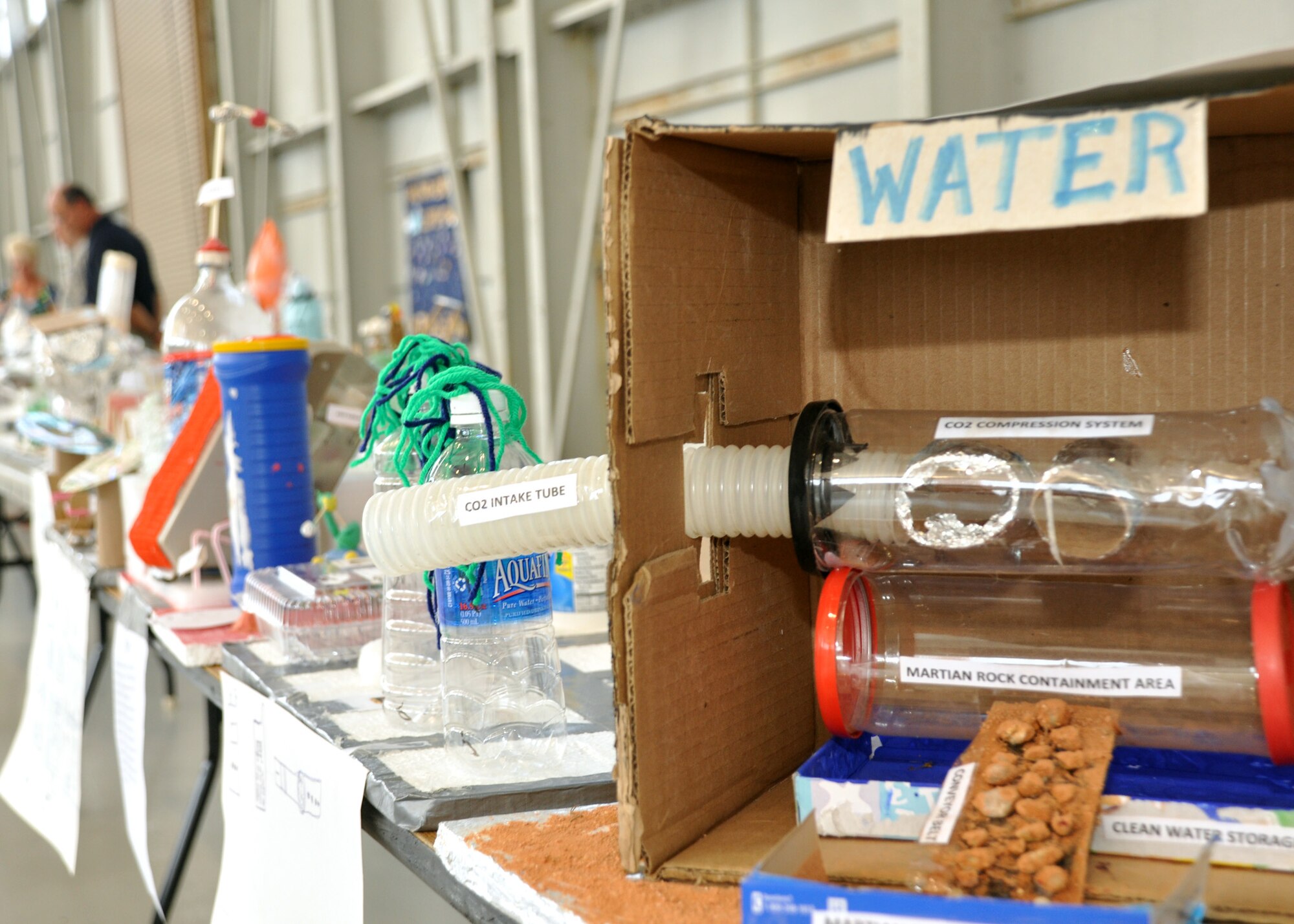 Problem-solving projects wait to be judged during the Marsville event at Eglin Air Force Base April 16.  Children were asked to create a project using only recyclable materials that would solve a core component problem of living on Mars.  More than 120 students from Wright, Longwood and Valparaiso elementary schools gathered on Eglin for a single mission: build a life-sustaining pod on Mars.   The 15th annual Marsville event is a collaborative effort between Eglin and the surrounding community's elementary school fifth-grade students, and faculty members. One of its top goals is to encourage students to pursue careers in science and engineering.  (U.S. Air Force photo/Staff Sgt. Stacia Zachary.)