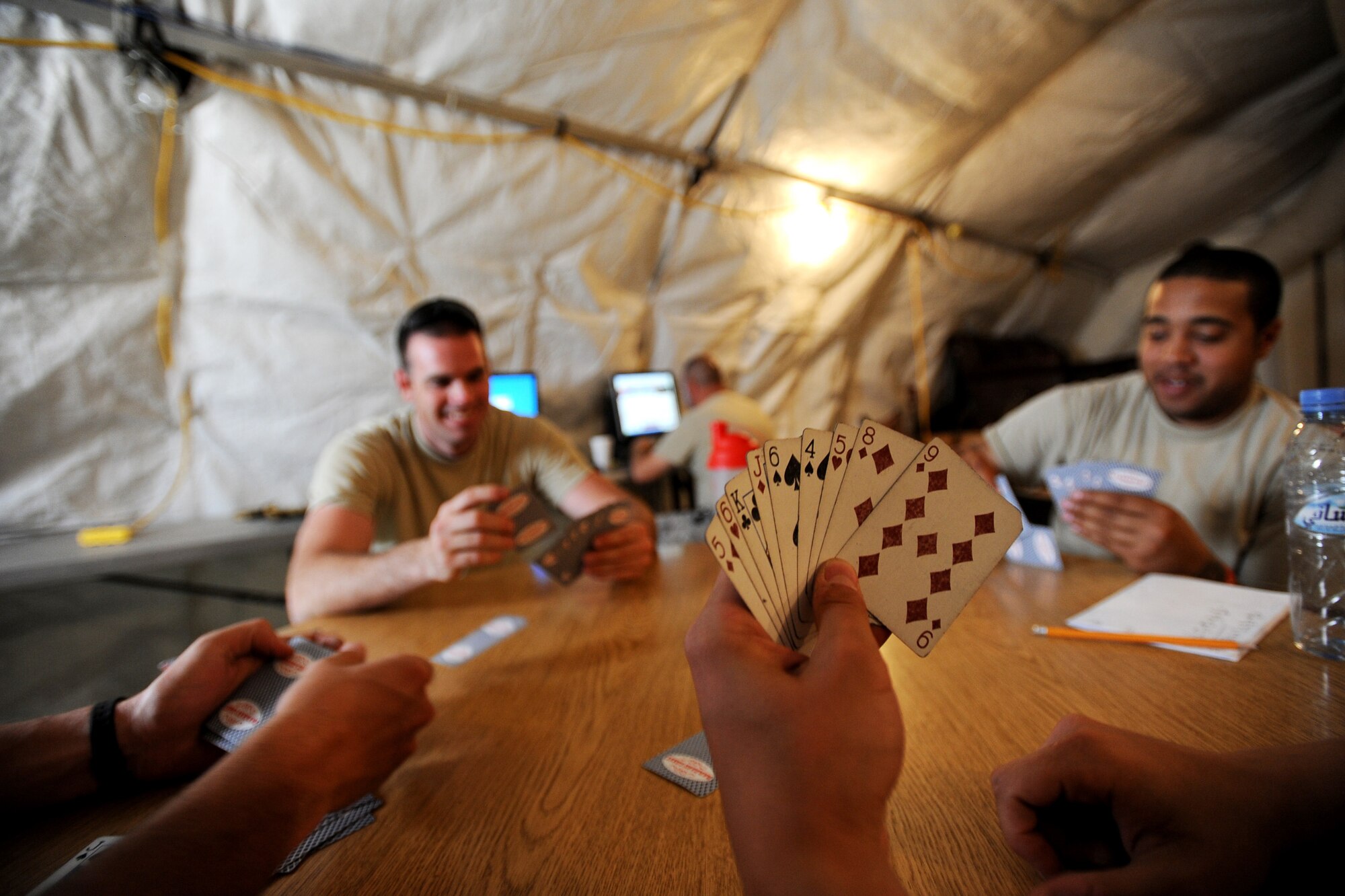 Senior Airman Rick Varney center, an HH-60G Pave Hawk structural maintenance Airman assigned to the 451st Expeditionary Aircraft Maintenance Squadron helicopter maintenance unit, plays a game of spades along with his co-workers, April, 16, 2010, at Camp Bastion, Afghanistan. The HMU, with Airmen from 15 different Air Force specialty codes, are making a difference in Afghanistan, keeping rescue missions in the air for Coalition Forces and Afghan citizens. (U.S. Air Force photo/Staff Sgt. Manuel J. Martinez/released)

