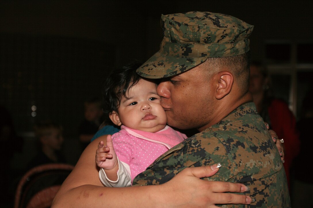 Petty Officer 1st Class Damien Brown, hospital corpsman, Headquarters Battalion, 3rd Marine Division, III Marine Expeditionary Force, kisses his daughter Destiny during a welcoming party after a nine-month deployment to eastern Afghanistan in support of Operation Enduring Freedom Tuesday.