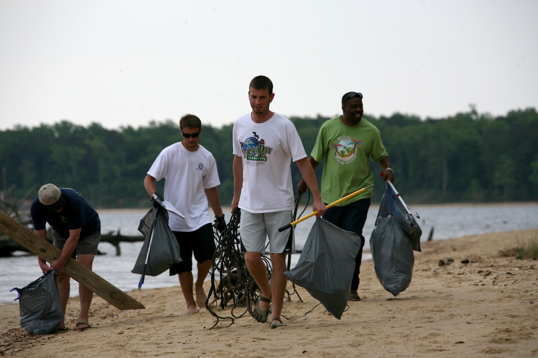 (From left to right) Bill Belli, Matt Wallin, Will R. Potter and Ruan Stewart, all employees of the air station’s Environmental Affairs Department, carry handfuls of trash for the Grants Landing beach cleanup in celebration of Earth Week, April 21. There were more than 20 volunteers present.