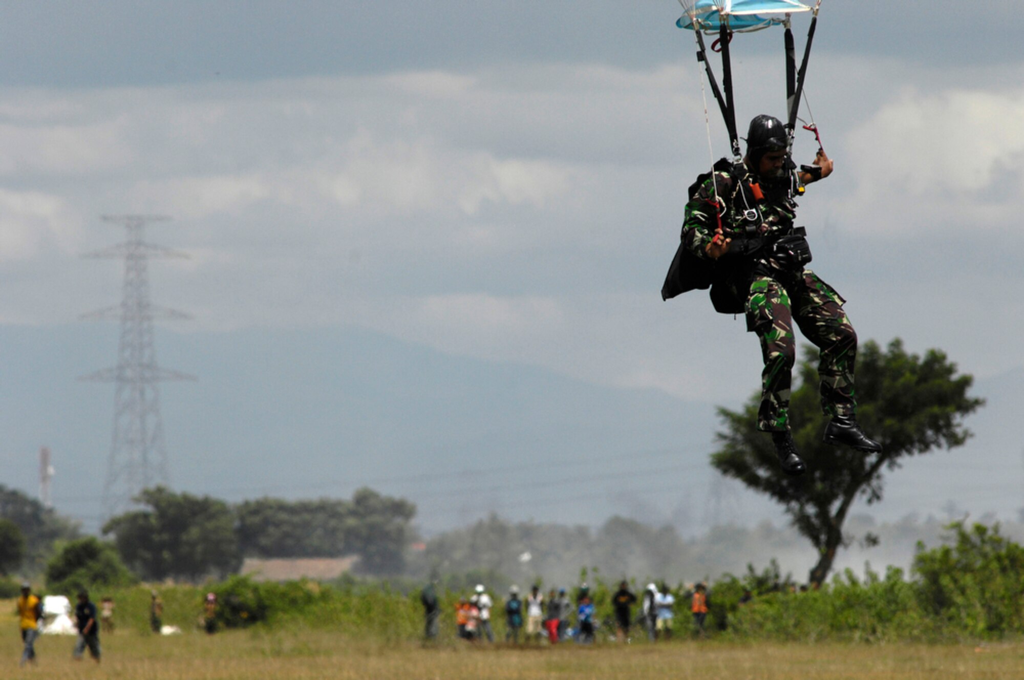 Local children watch as an Indonesian soldier prepares to land April 21, 2010, after jumping from a C-130 Hercules from Yokota Air Base, Japan, during Cope West 10 at Halim Air Base, Indonesia.  Cope West is a Pacific Air Forces-sponsored bilateral tactical airlift exercise involving the U.S. and Indonesian air forces. The exercise is designed to advance interoperability between the two services, and promote cooperation and unity of purpose. (U.S. Air Force photo/Tech Sgt. Cohen A. Young)
