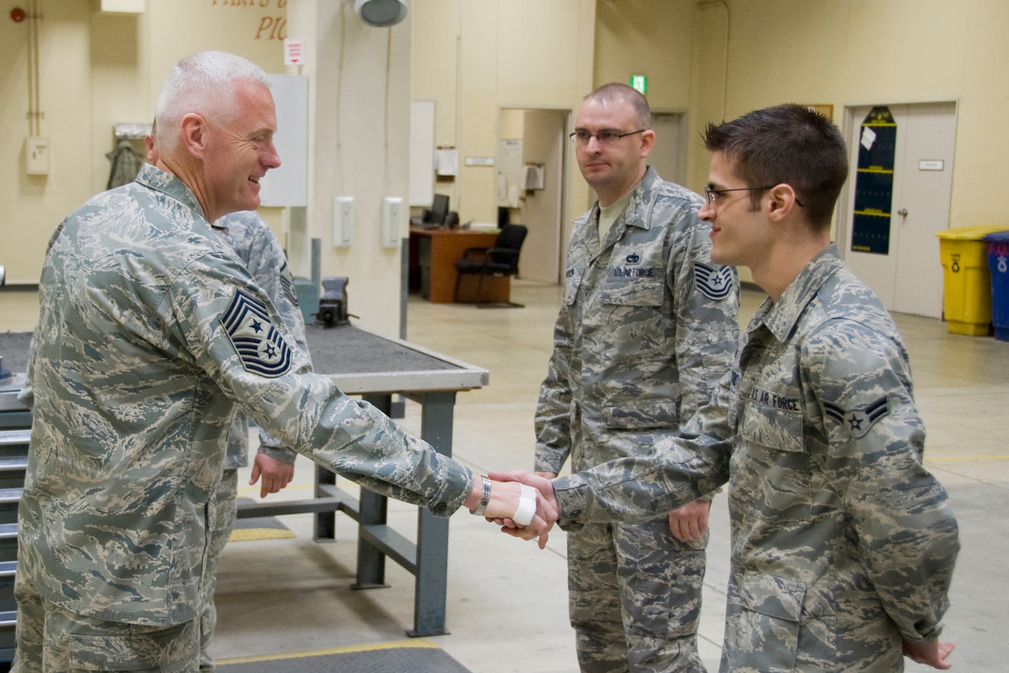 MISAWA AIR BASE, Japan -- Chief Master Sgt. Richard Kaiser, 5th Air Force command chief master sergeant, shakes hands with Airman 1st Class Kyle Moore, 35th Maintenance Squadron aircraft structure maintenance journeyman, April 20 at the aircraft structure maintenance shop. Chief Kaiser congratulated Airman Moore on recently being named a senior airman below-the-zone selectee. (U.S. Air Force photo/Senior Airman Jamal D. Sutter)