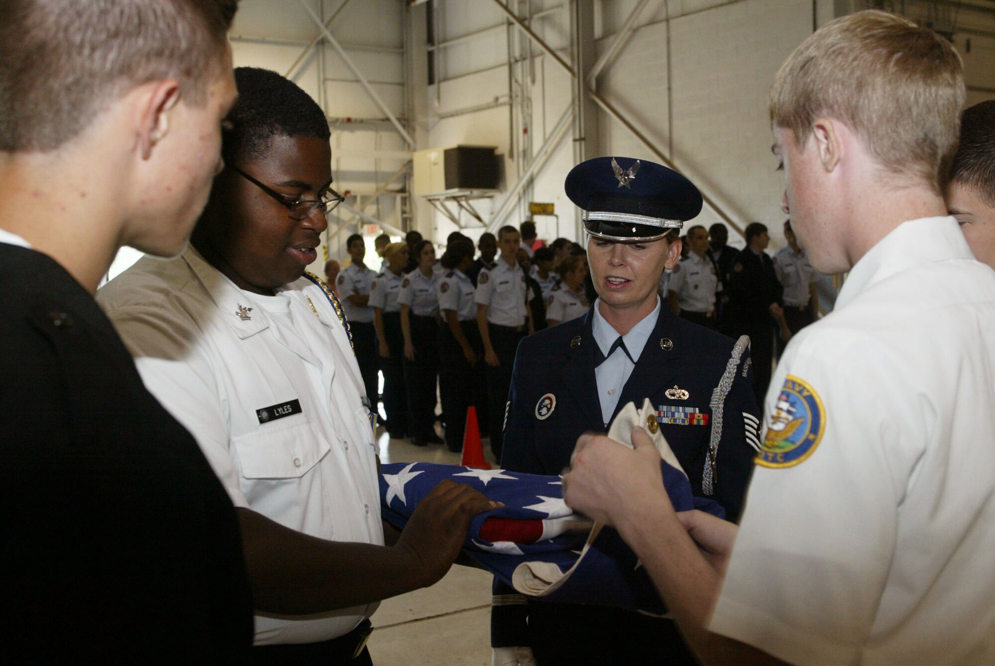 Tech. Sgt. Lisa M. Whitley from the 94th Airlift Wing Honor Guard with assistance from Navy cadets from Hillgrove High School, demonstrates the proper way to conduct the flag folding ceremony during the JROTC orientation flights April 14. Orientation flights are designed to introduce youth to general aviation and military opportunities through hands-on interaction with aircraft, equipment and personnel. (U.S. Air Force photo/Don Peek)