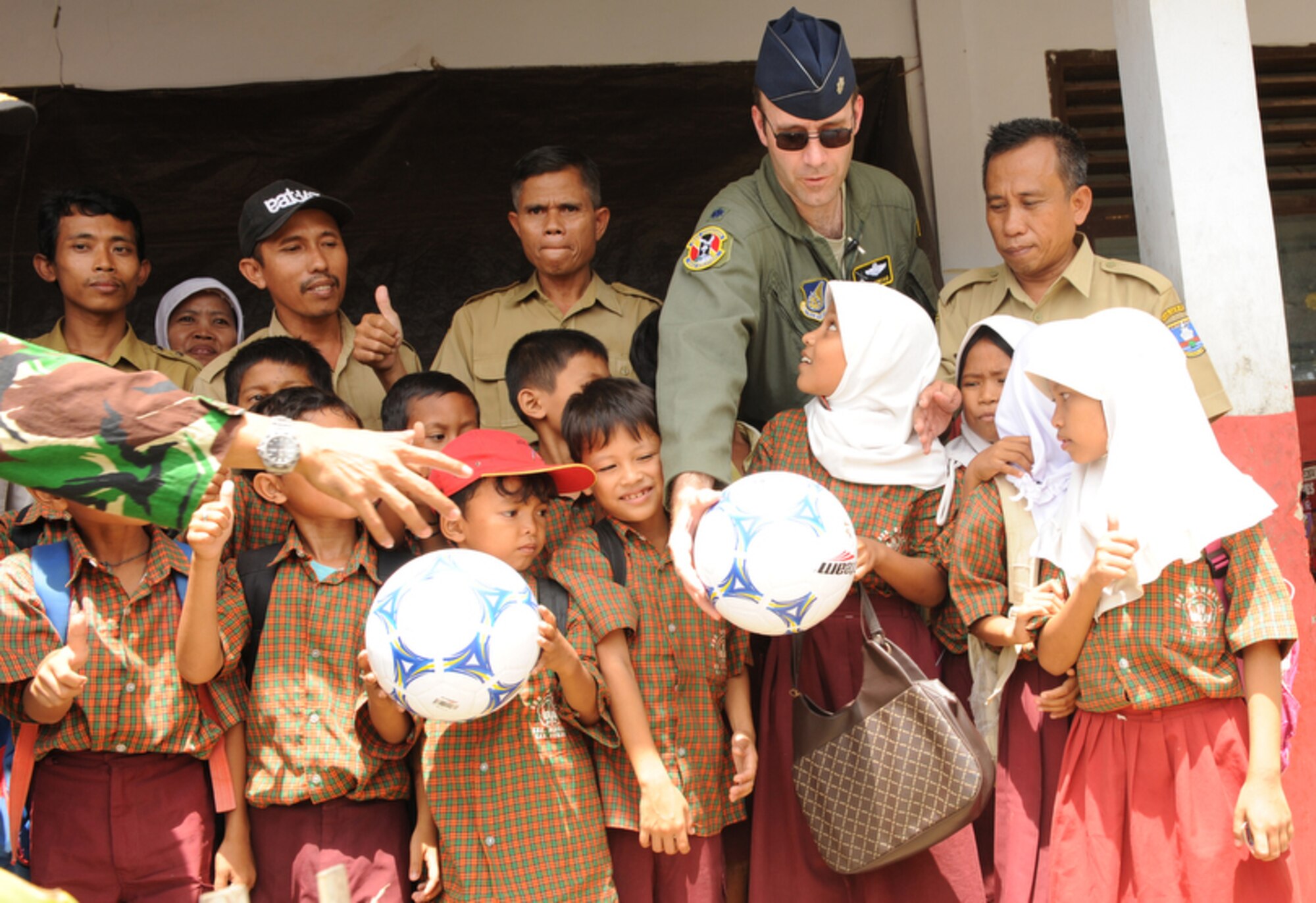 Lt. Col. Dave Kincaid passes a soccer ball to a young girl April 21 during a community relations event at the Sd Negeri Gembor 2 Elementary School in the Lanud Gorda Binuang area of Indonesia. Over 1,200 pounds of clothes, toys and sports equipment from Yokota Air Base, Japan, were donated to the school.  Colonel Kincaid is assigned to Yokota as the 36th Airlift Squadron commander.  He and other Yokota Airmen are participating in Cope West 10, a Pacific Air Forces-sponsored bilateral tactical airlift exercise involving the U.S. and Indonesian air forces. The exercise is designed to advance interoperability between the two services, and promote cooperation and unity of purpose. (U.S. Air Force photo/Tech Sgt. Cohen A. Young)