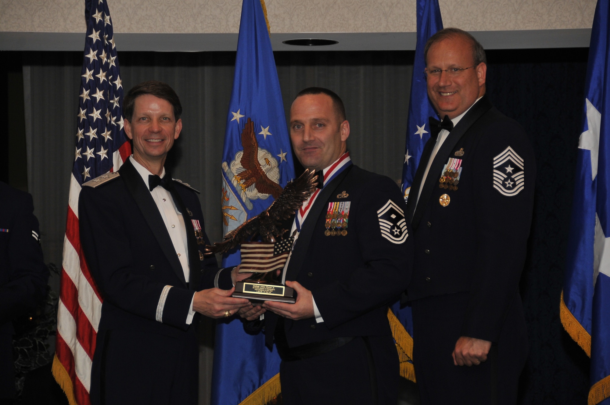 Air Force District of Washington Commander Maj. Gen. Darrell D. Jones, left, and AFDW Command Chief Master Sgt. Pat Battenberg, right, presented the AFDW the 2009 Annual  First Sergeant of the Year award to Master Sgt. John L. Flynn, Jr.,  316th Wing Civil Engineering Squadron, Andrews, during the AFDW Annual Awards Banquet April 16, 2010. The banquet was held at the Bolling Club, Bolling AFB, Washington D.C. (U.S. Air Force photo by Senior Airman Marleah Miller)