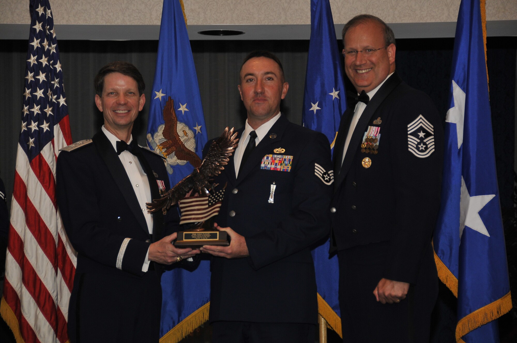 Air Force District of Washington Commander Maj. Gen. Darrell D. Jones, left, and AFDW Command Chief Master Sgt. Pat Battenberg, right, presented the AFDW the 2009 Military Volunteer of the Year  award to Staff Sgt. Kelly McKinley, who accepted the award on behalf of Staff Sgt. Adam Furtado, U.S. Air Force Honor Guard, Bolling, during the AFDW Annual Awards Banquet April 16, 2010. The banquet was held at the Bolling Club, Bolling AFB, Washington D.C. (U.S. Air Force photo by Senior Airman Marleah Miller)