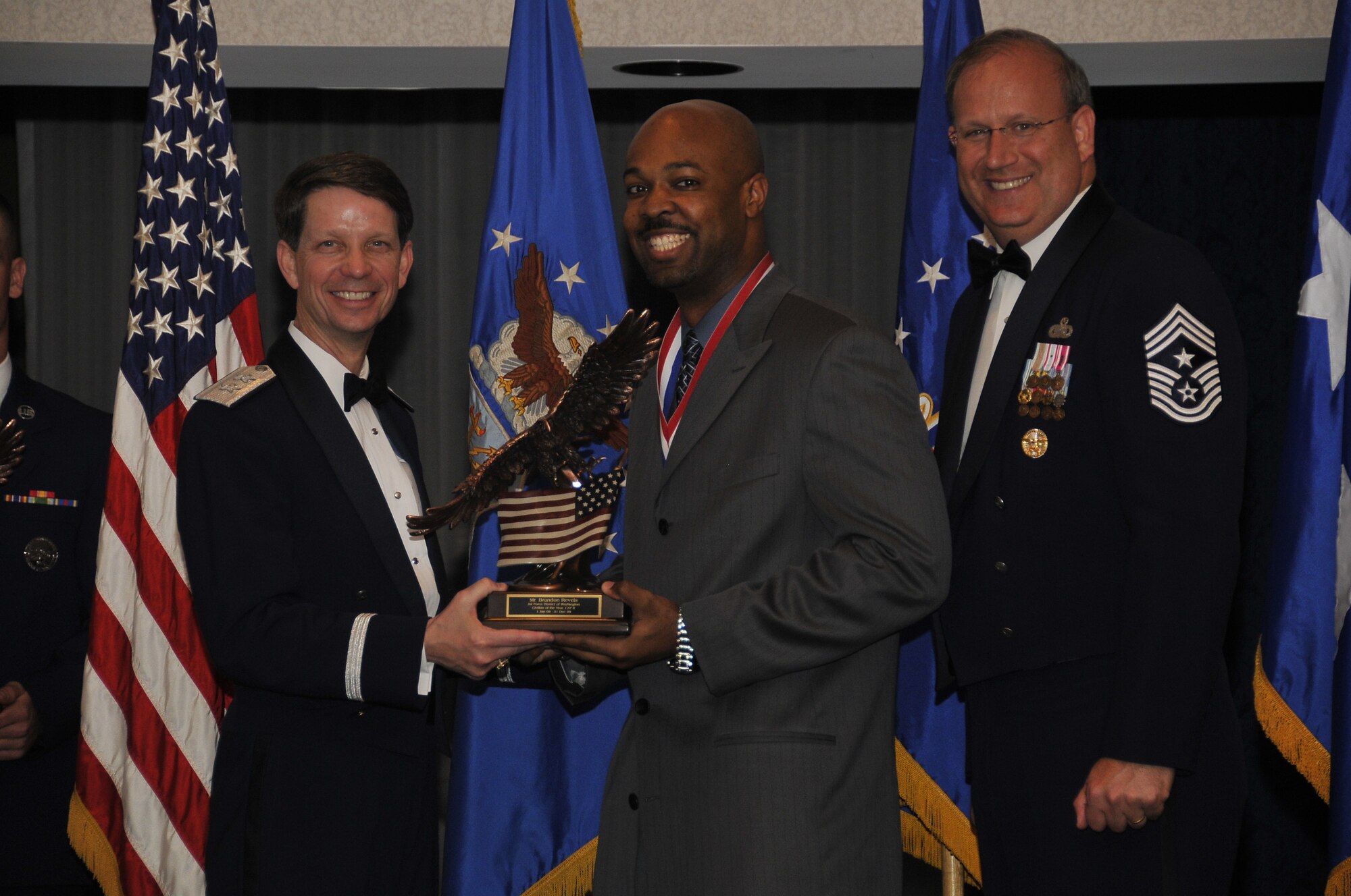 Air Force District of Washington Commander Maj. Gen. Darrell D. Jones, left, and AFDW Command Chief Master Sgt. Pat Battenberg, right, presented the  AFDW the 2009 Annual  Civilian of the Year Category ll award to Brandon Revels, 579th Medical Group, Bolling during the AFDW Annual Awards Banquet April 16, 2010. The banquet was held at the Bolling Club, Bolling AFB, Washington D.C. (U.S. Air Force photo by Senior Airman Marleah Miller)