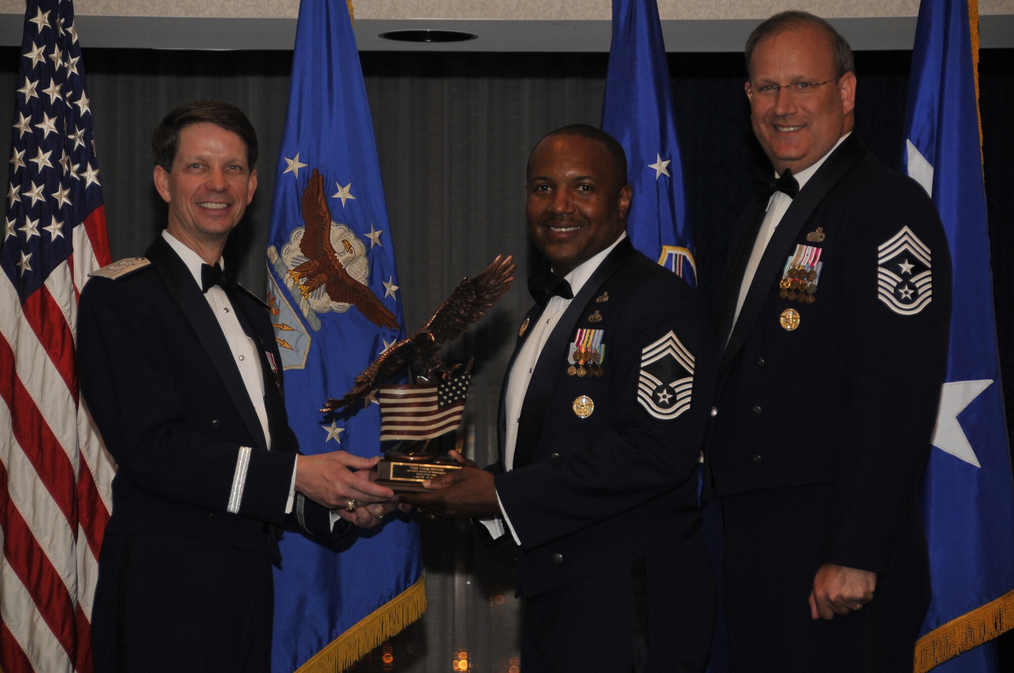 Air Force District of Washington Commander Maj. Gen. Darrell D. Jones, left, and AFDW Command Chief Master Sgt. Pat Battenberg, right, presented the AFDW 2009  NCO of the Year award to Chief Master Sgt. John Sneed, who accepted the award on behalf of Tech. Sgt. Craig A. Groves, 844th Communications Squadron, Pentagon, Washington D.C., during the AFDW Annual Awards Banquet April 16, 2010. The banquet was held at the Bolling Club, Bolling AFB, Washington D.C.  (U.S. Air Force photo by Senior Airman Marleah Miller)