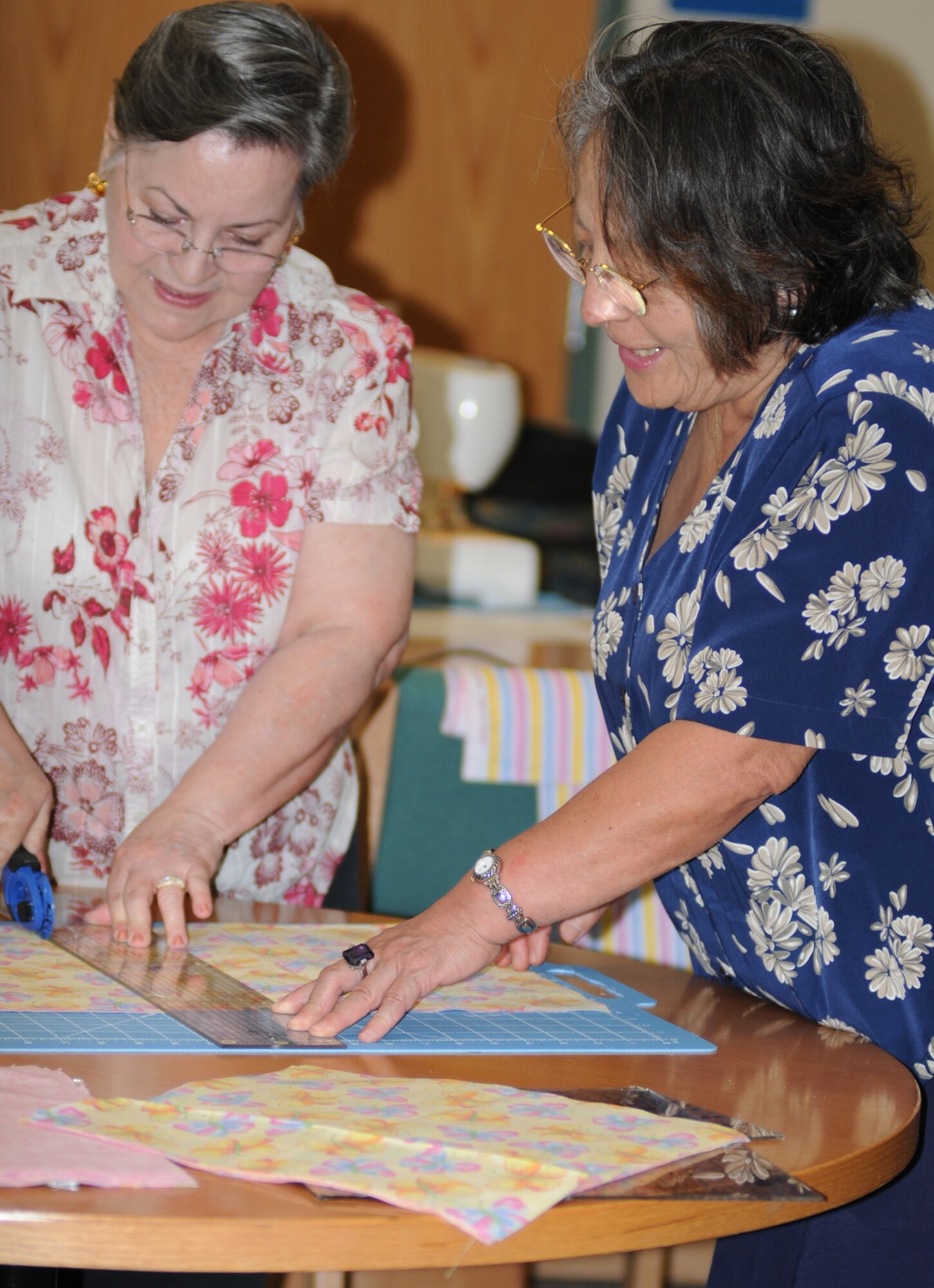 Olga Ramon, left, and Rose Bender cut fabric during a quilting class at McBride Library April 17 as part of National Library Week.  (U.S. Air Force photo by Kemberly Groue)