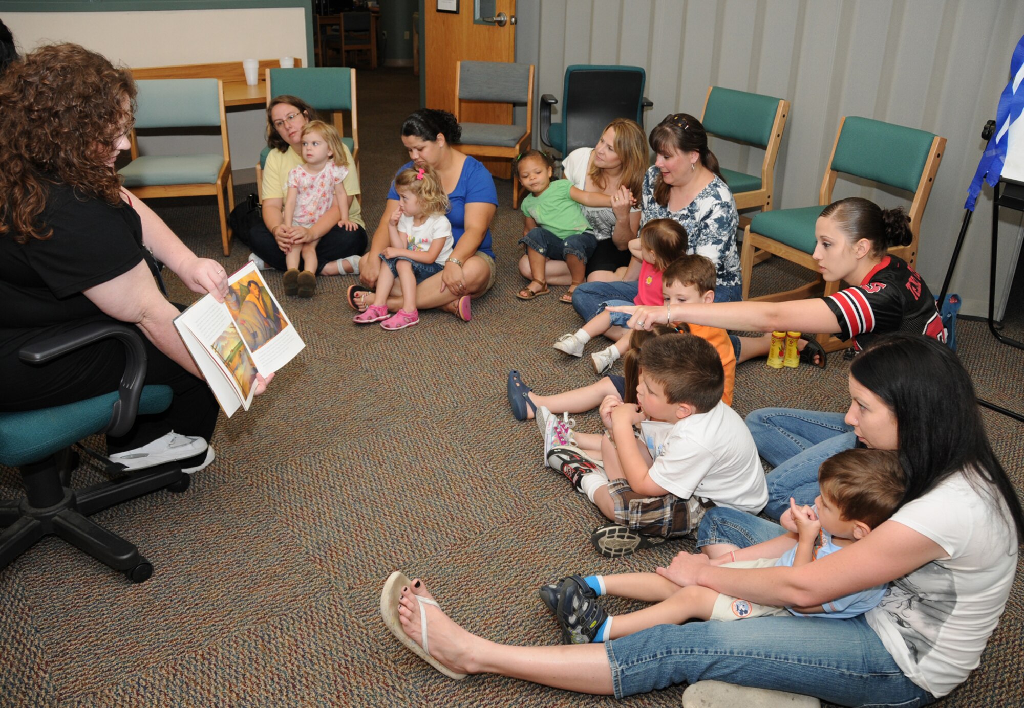 CSC contractor Kathy Savelio shows pictures to children while volunteer Mireya Alexander reads "Tomas and the Library Lady" during a children's story time at McBride Library April 14 as part of National Library Week.  (U.S. Air Force photo by Kemberly Groue)