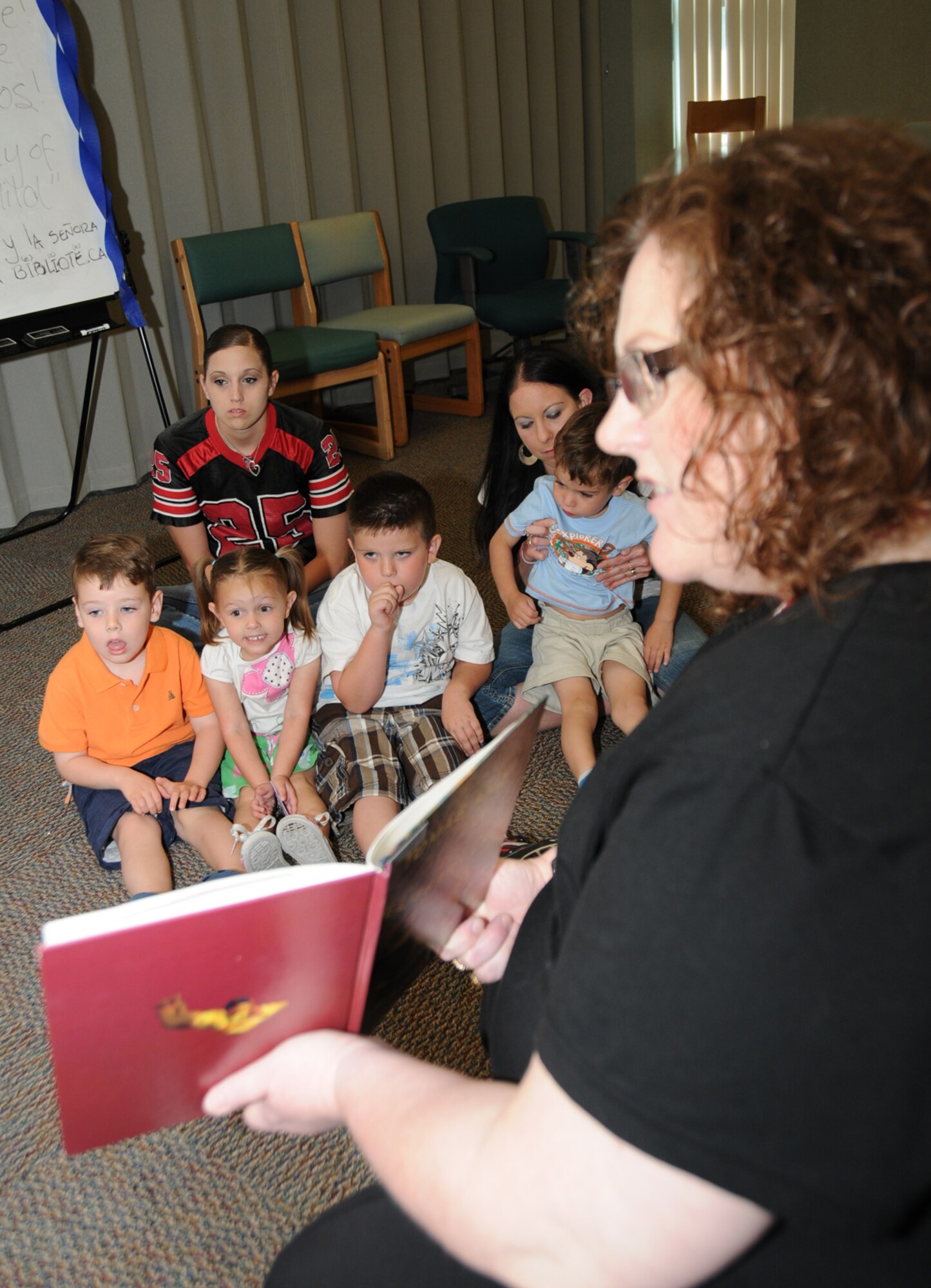 CSC contractor Kathy Savelio shows pictures to children while volunteer Mireya Alexander reads "Tomas and the Library Lady" during a children's story time at McBride Library April 14 as part of National Library Week.  (U.S. Air Force photo by Kemberly Groue)