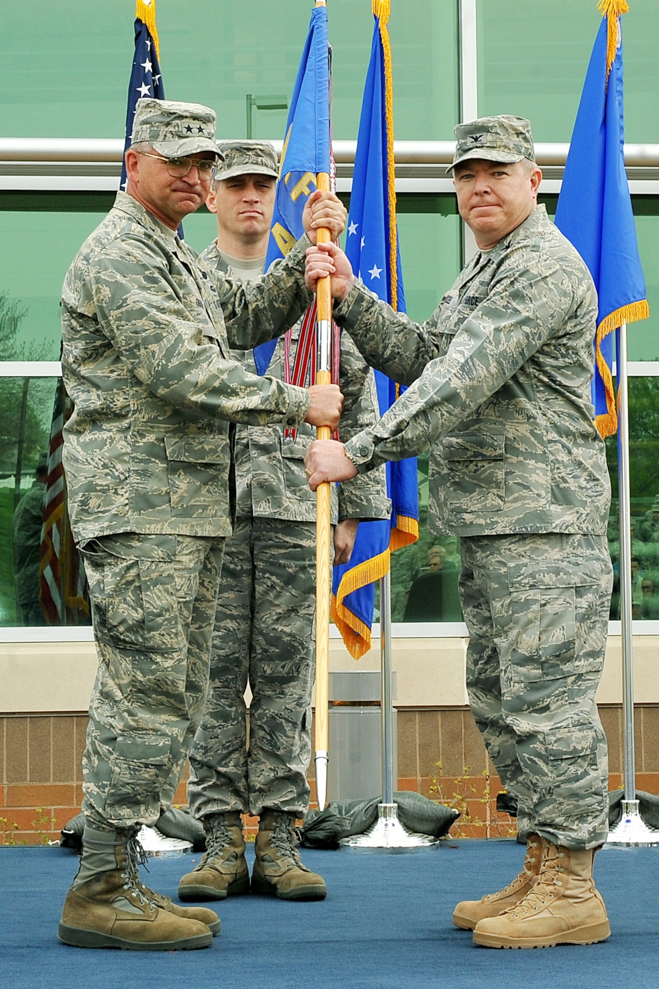 OFFUTT AIR FORCE BASE, Neb. -- Maj. Gen. Marke Gibson, Air Force director of operations and deputy chief of staff for operations, plans and requirements, presents Col. Robert L. Russell, Jr., incoming AFWA commander, with the AFWA guideon, during a change of command ceremony here April 20 in front of the Lt. Gen. Thomas S. Moorman building. The agency is comprised of more than 1,400 active-duty members, civil service employees and contractors at 14 operating locations around the world which provide centralized weather products and services, including climatological and space weather support to all branches of the armed forces. U.S. Air Force photo by Charles Haymond