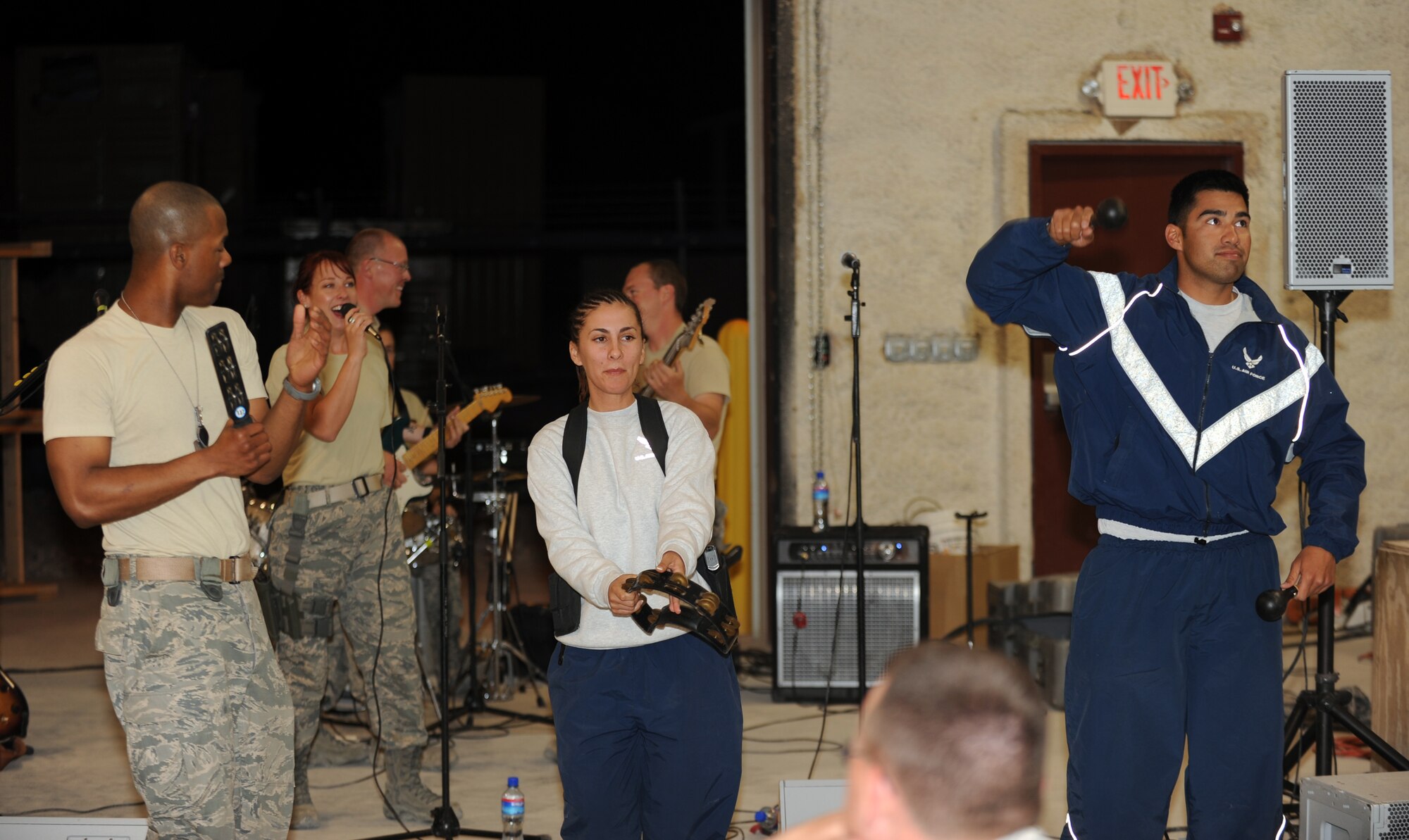 (Left) Master Sgt. Aaron Miles, non-commissioned officer in charge of U.S. Air Forces Central Band Reserve Generation, leads Senior Airman Lorenda Salazar and Senior Airman Luis Murillo, 455th Expeditionary Civil Engineers Squadron Force Protection Flight,  , in a sing along during a concert at Bagram Airfield, Afghanistan, April 17, 2010. Airman Salazar is deployed from Anderson Air Base, Guam and Airman Murillo is deployed from Kadena AB, Japan. The band is completing a two-month tour of Southwest Asia and is deployed from Robins Air Force Base, Ga.  (U.S. Air Force photo by/ Staff Sgt. Richard Williams)