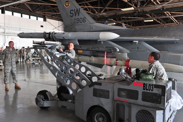 SHAW AIR FORCE BASE, S.C. -- Tech. Sgt. Samuel McDonnell (left), 20th Fighter Wing Maintenance Group, watches as Staff Sgt. James Seagle (center) and Airman 1st Class Hunter Haley, 79th Aircraft Maintenance Unit, load a missile into place April 16, 2010. Wing weapons standardization held the first Weapons Load Crew of the Quarter competition for 2010. The 55th and 79th Aircraft Maintenance Units weapons load crews competed against each other in a race against time. Both load crews were tasked to load two air intercept missiles, or AIM - 120s, and two air-to-ground missiles, also known as AGM - 88s, within 45 minutes. (U.S. Air Force photo/Airman 1st Class Amber E. N. Jacobs)